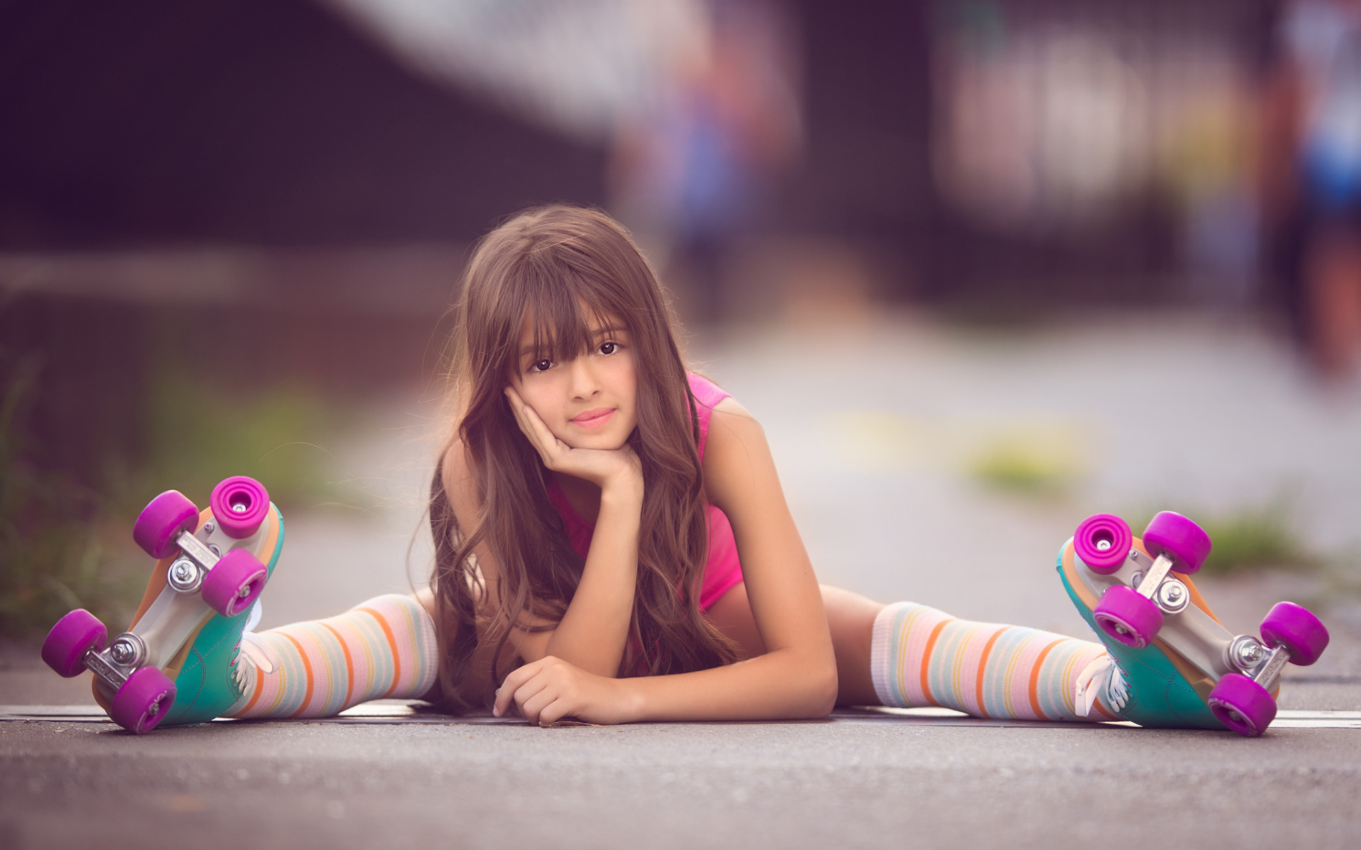 Маленькая девочка сидит на дороге в роликах