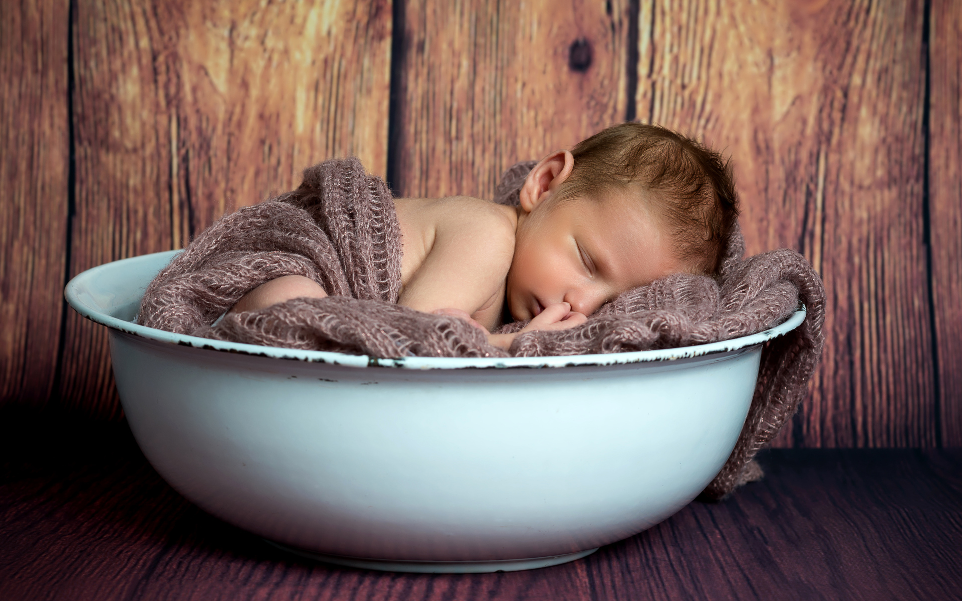 Новорожденный ребенок спит в белой миске