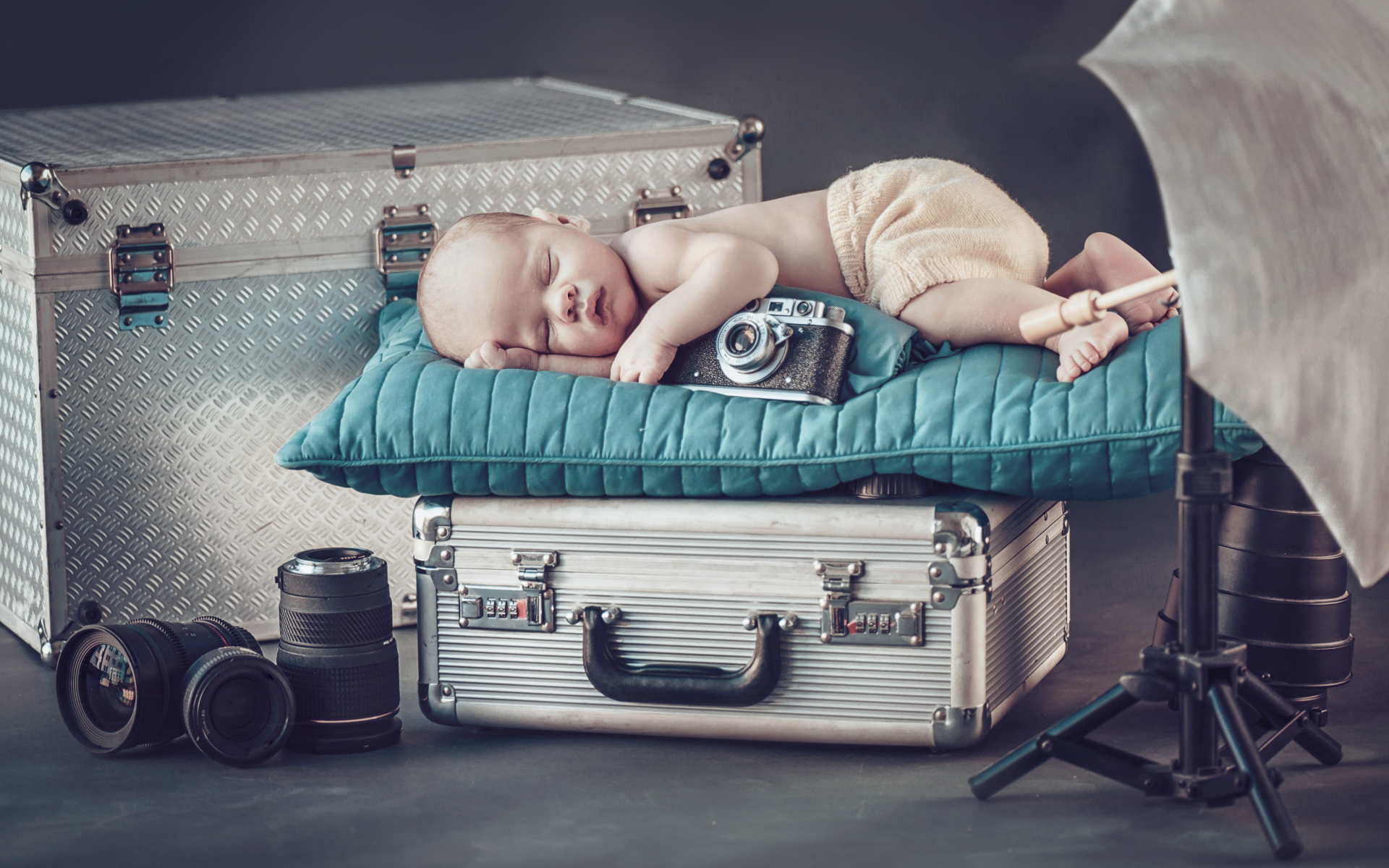 Спящий младенец с фотоаппаратом спит на чемодане
