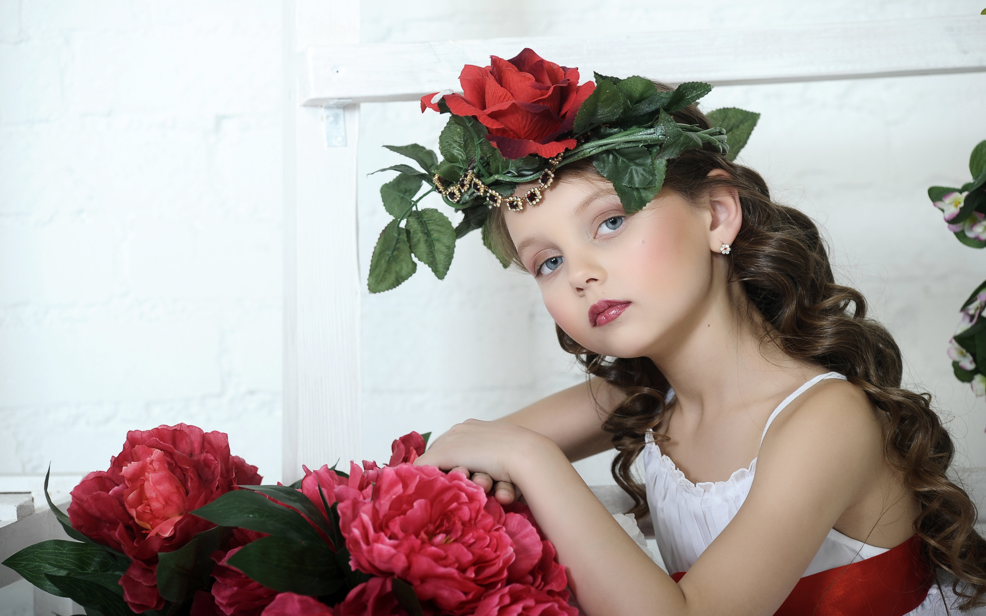 Красивая маленькая девочка с венком из роз на голове