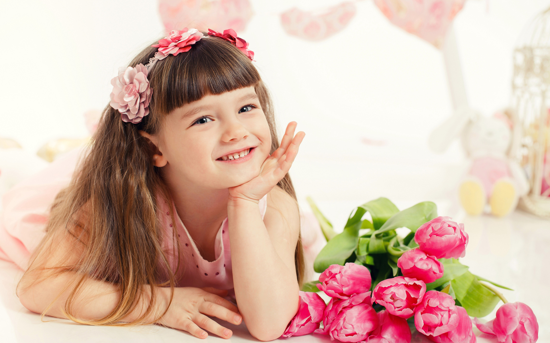 Красивая длинноволосая улыбающаяся девочка с букетом розовых тюльпанов