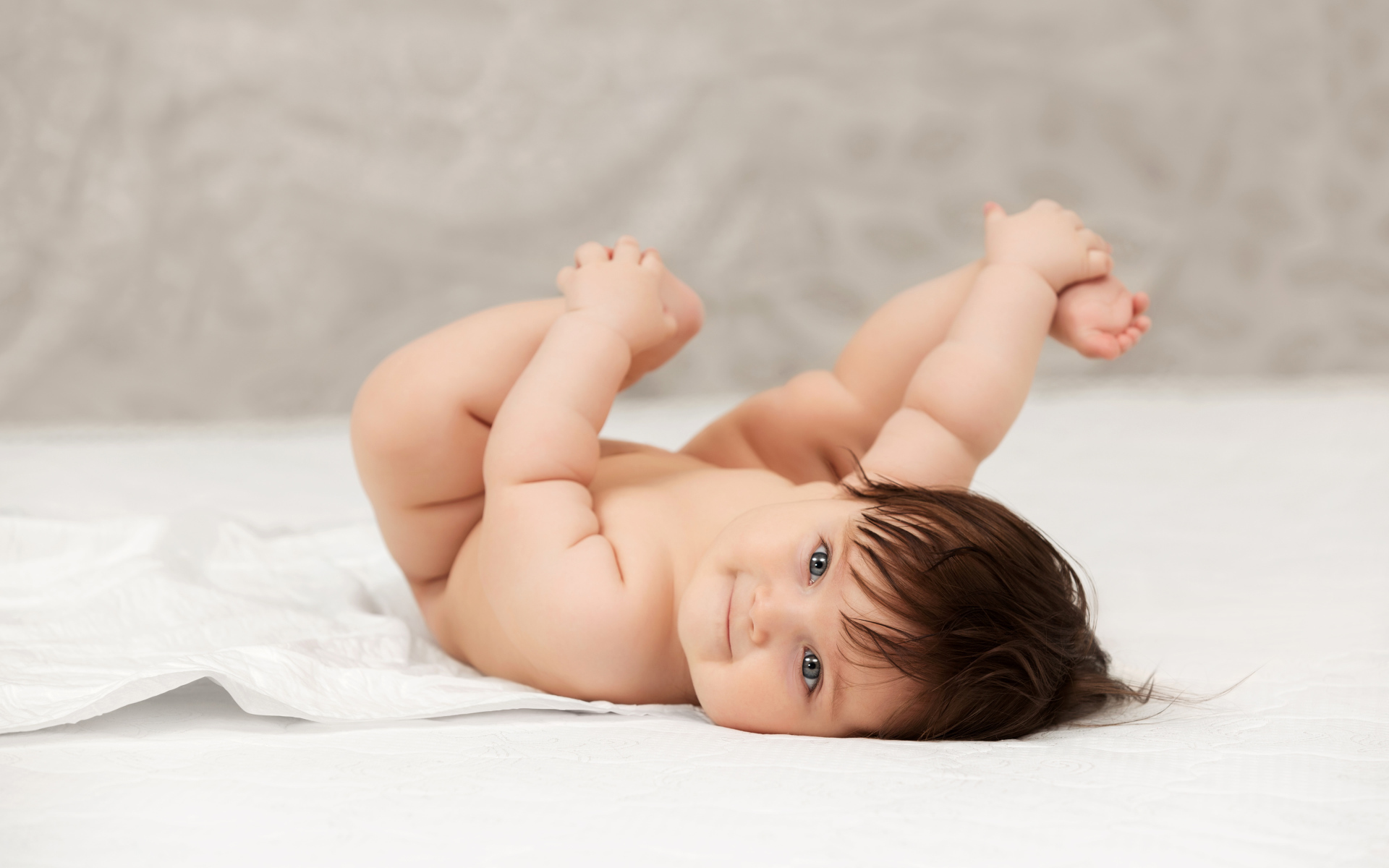Забавный младенец держится руками за ноги 