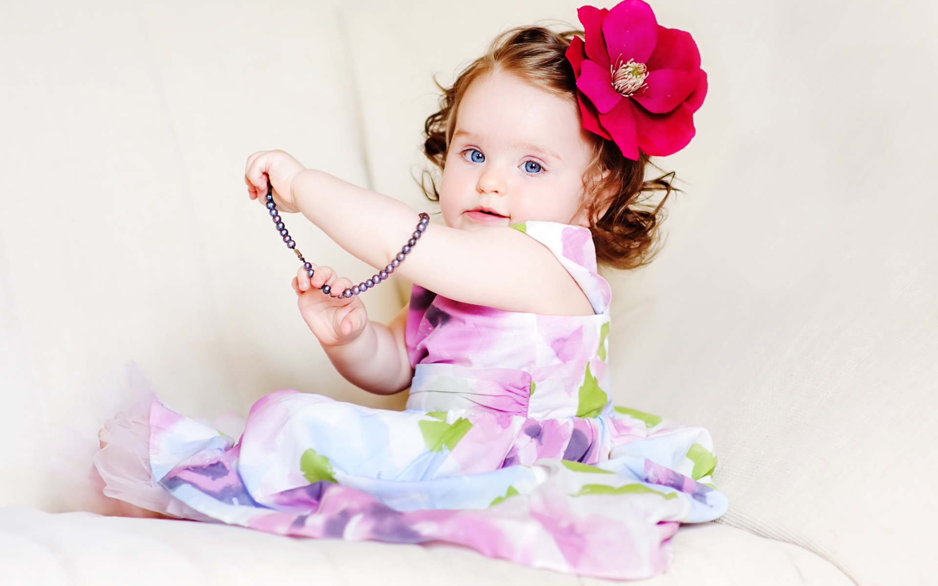 Маленькая голубоглазая девочка с красным цветком в волосах