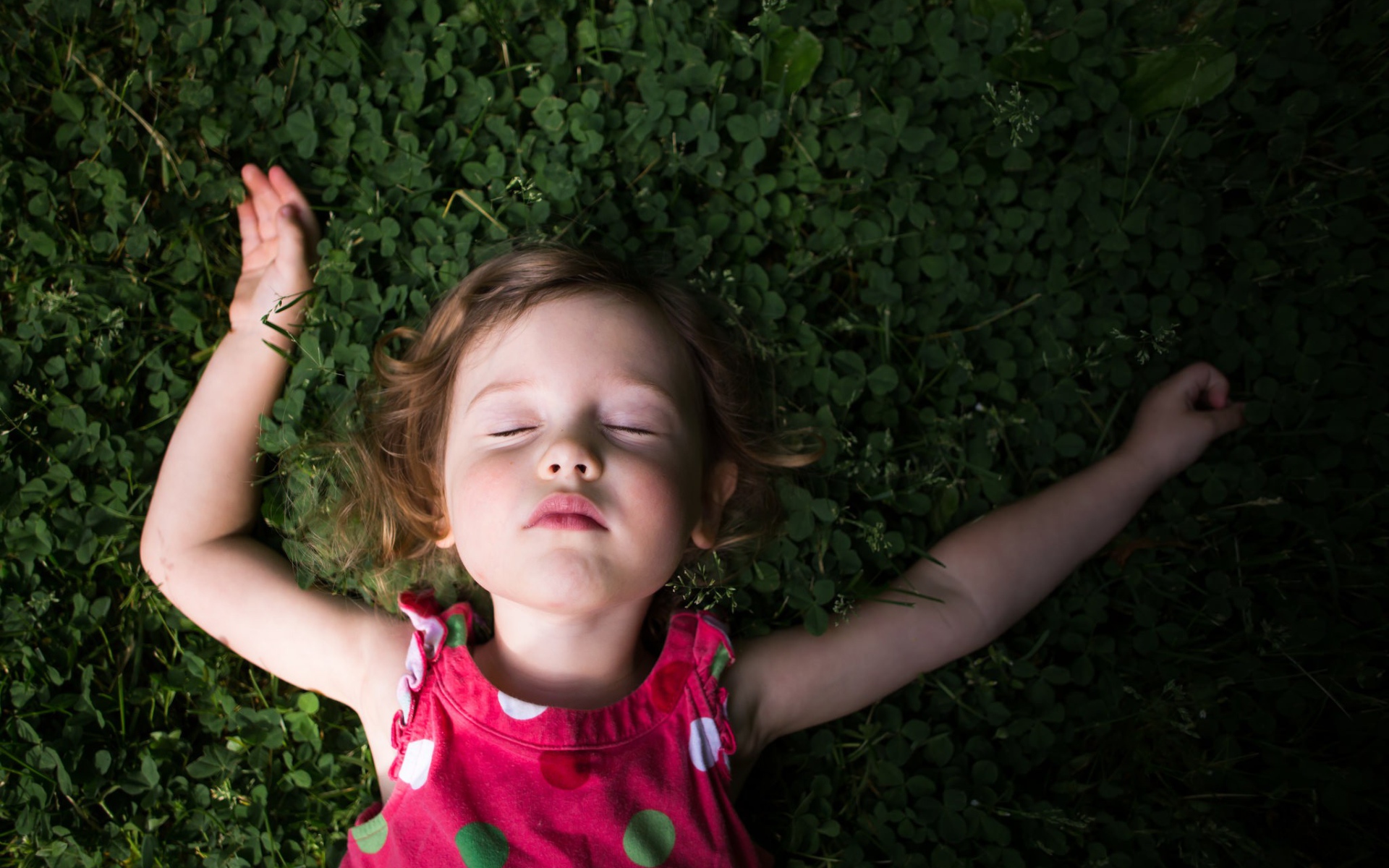 Маленькая девочка спит на зеленой траве 