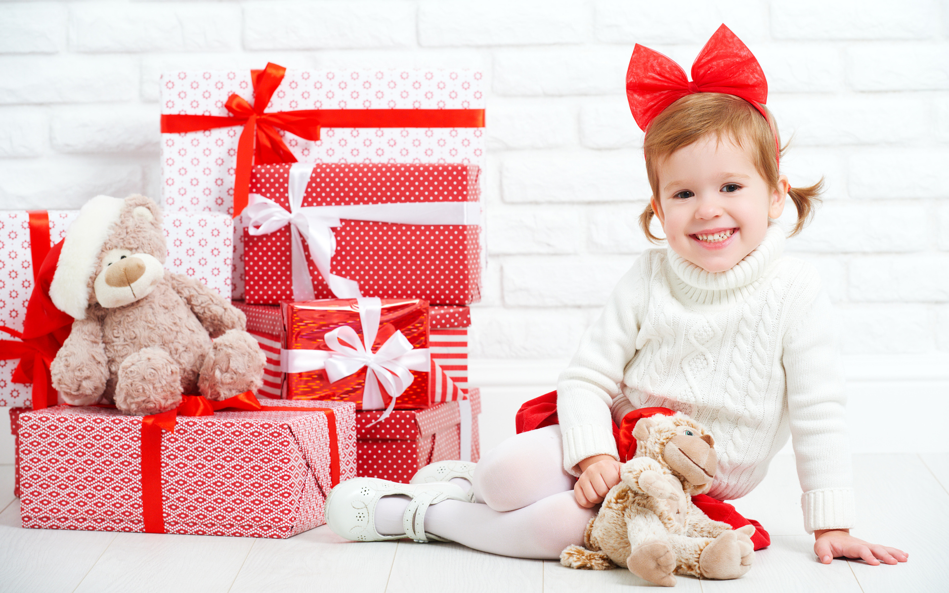 Маленькая улыбающаяся девочка с подарками на новый год