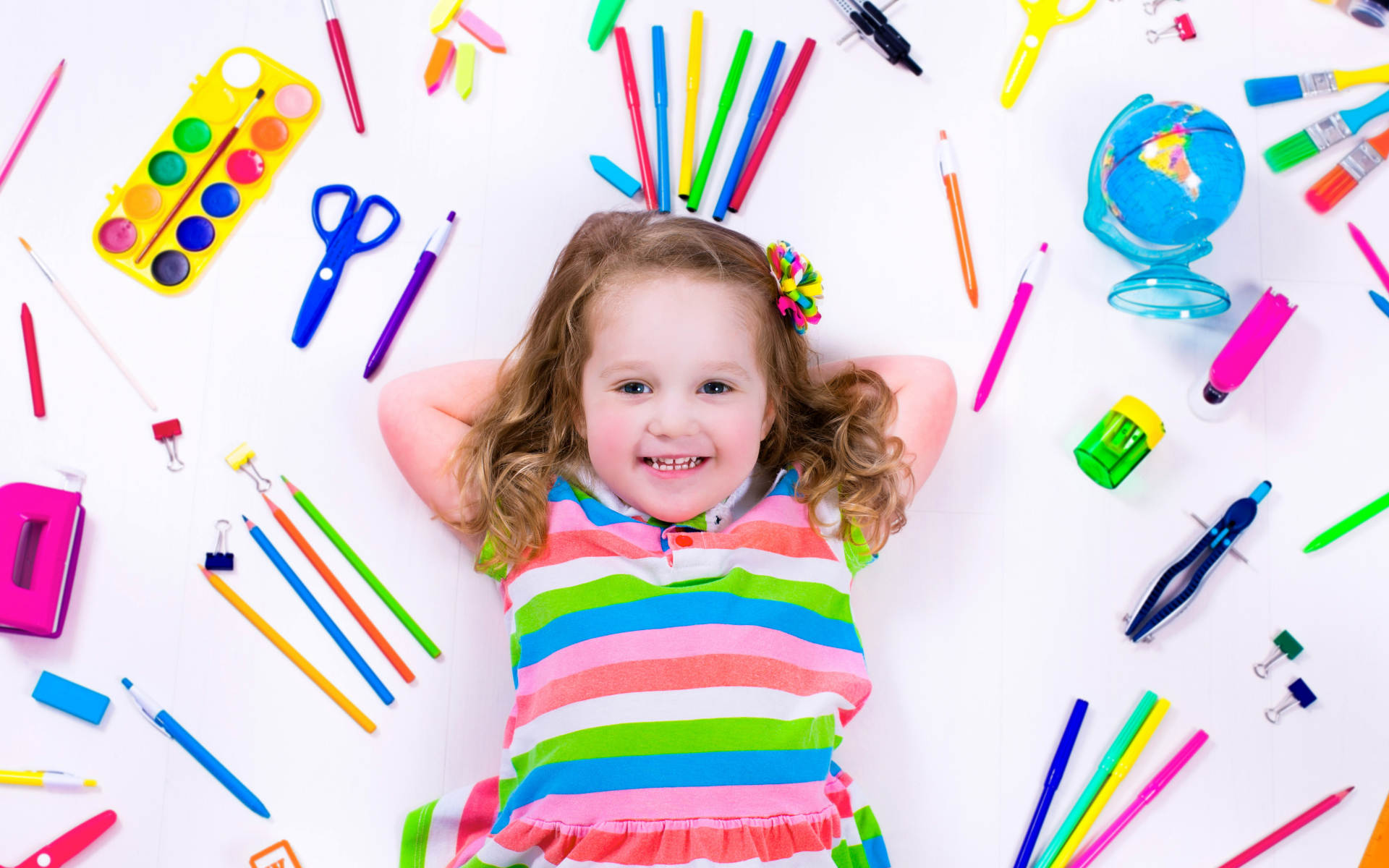 Маленькая улыбающаяся девочка со школьными принадлежностями