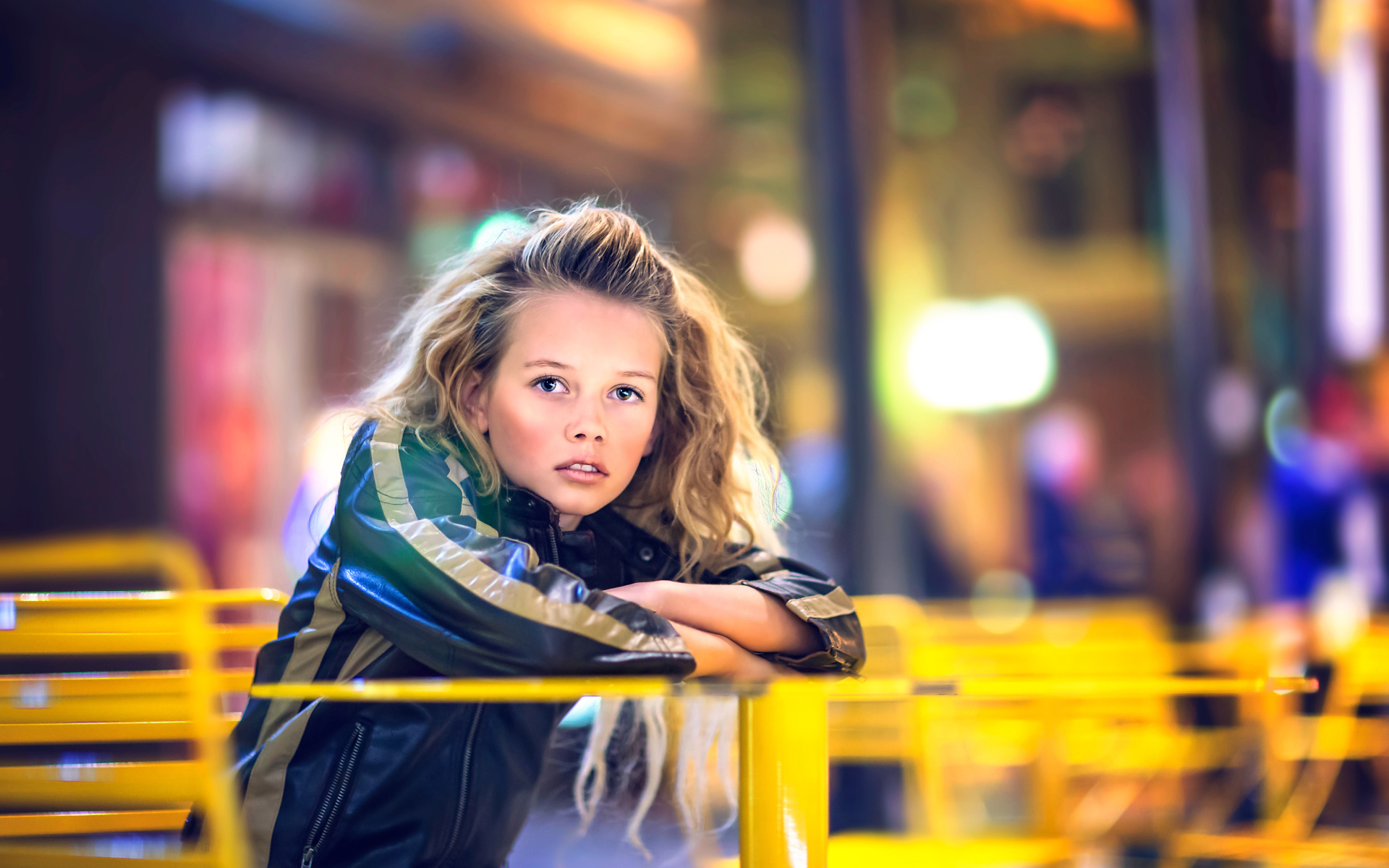 Длинноволосая девочка сидит на карусели