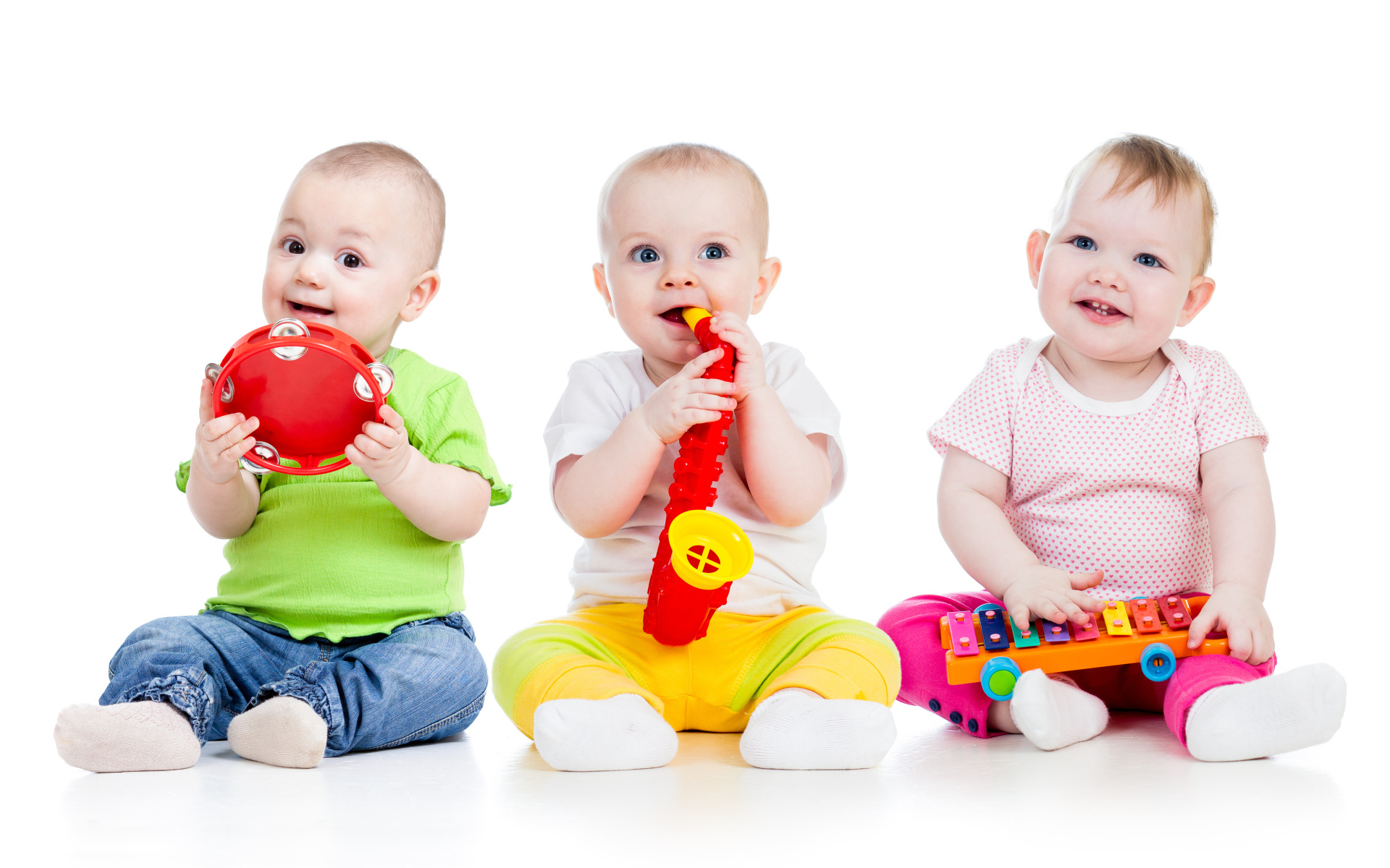 Три улыбающихся младенца играют на белом фоне