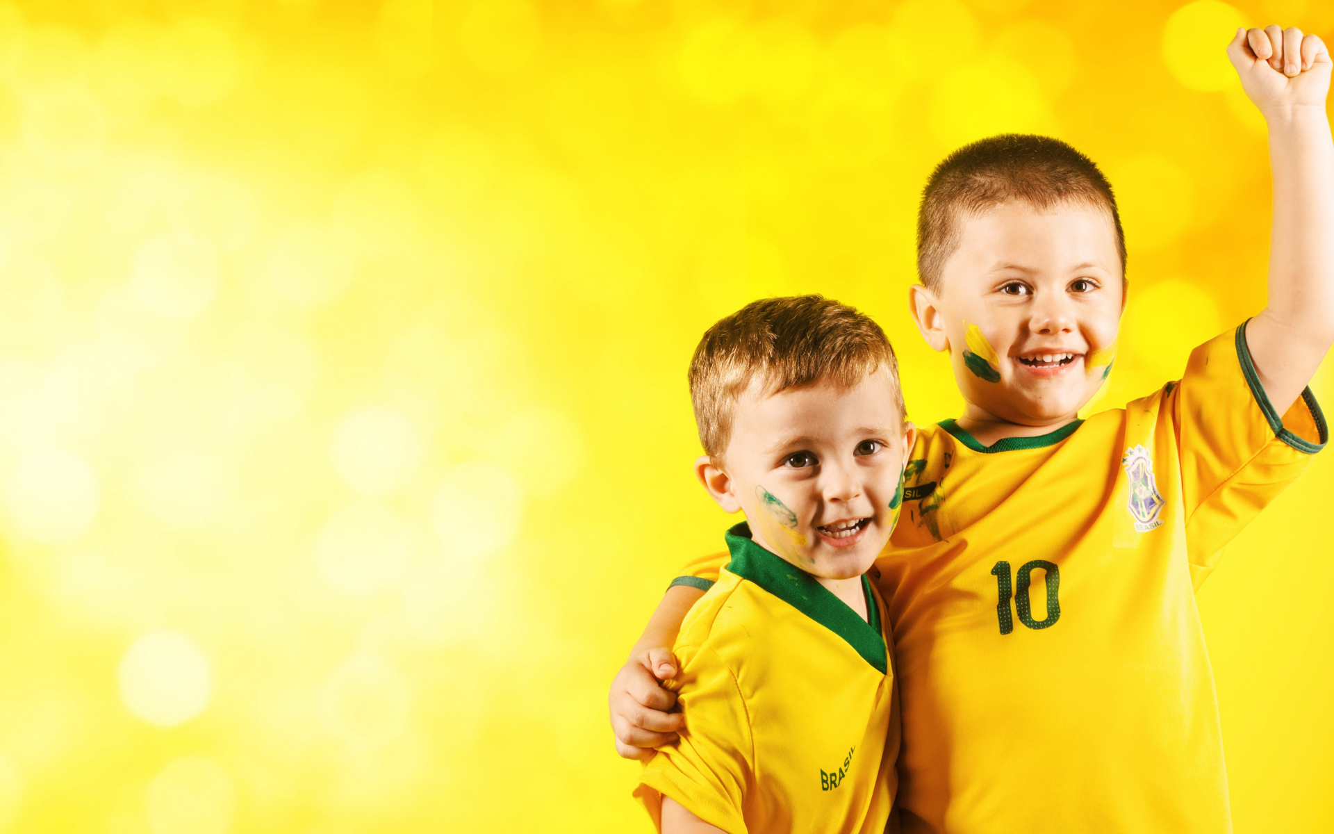 Два маленьких мальчика в спортивной форме на желтом фоне