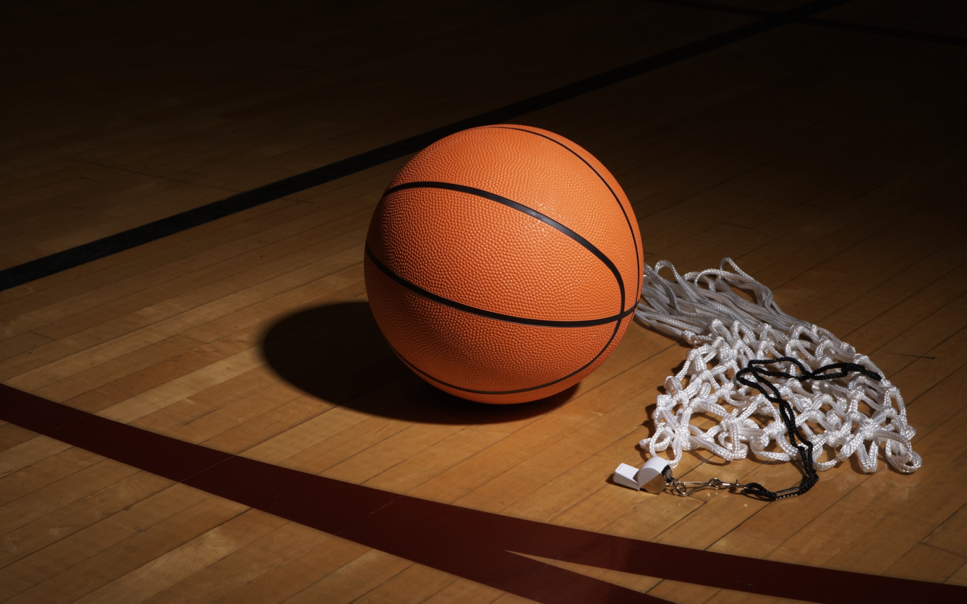 Баскетбольный мяч, свисток  и сетка на полу в спортзале 