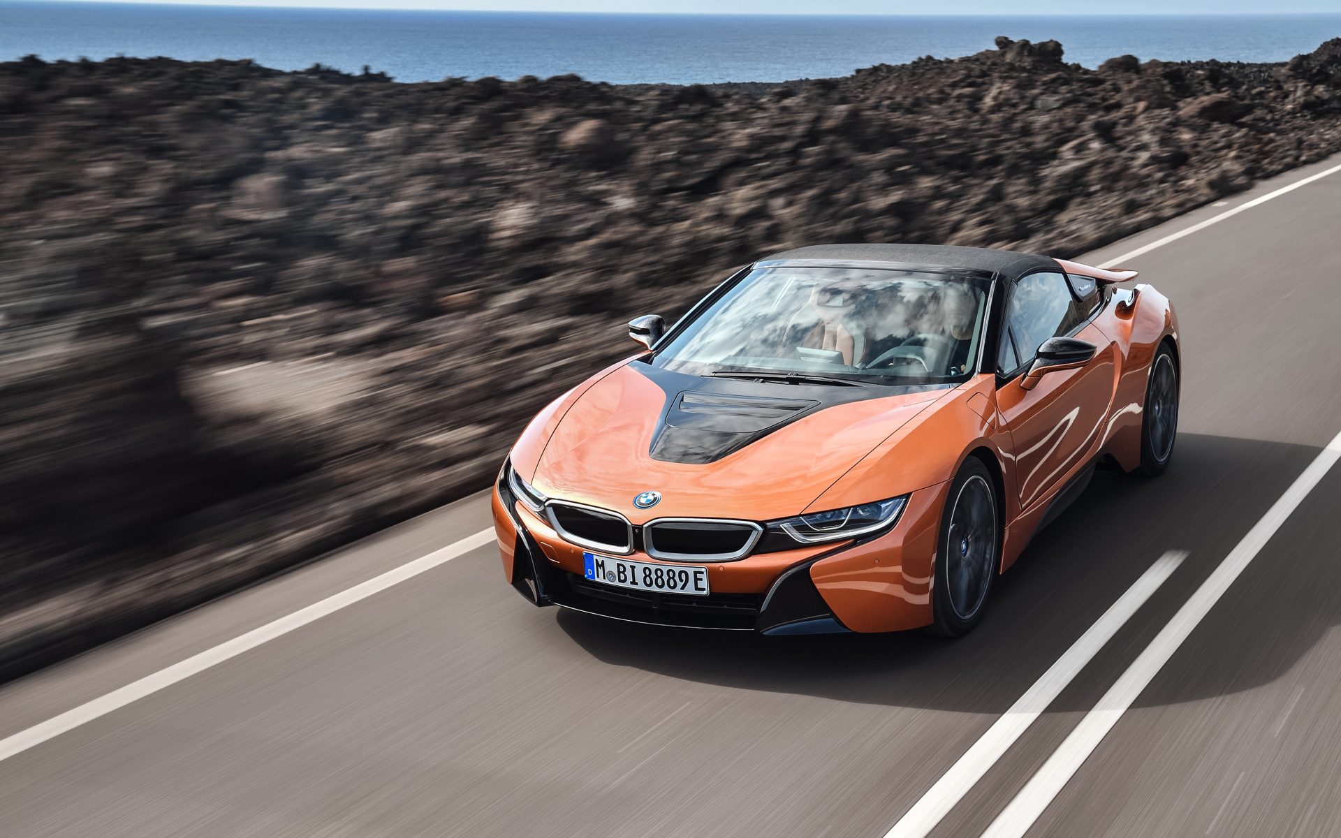 Оранжевый автомобиль BMW i8 Roadster, 2018 на скорости