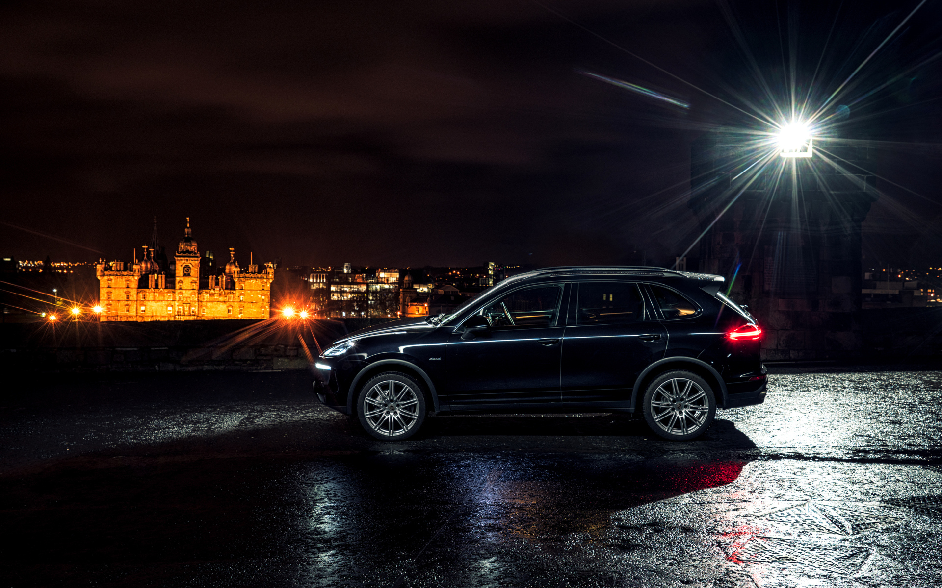Черный автомобиль Porsche Cayenne в свете фонаря 