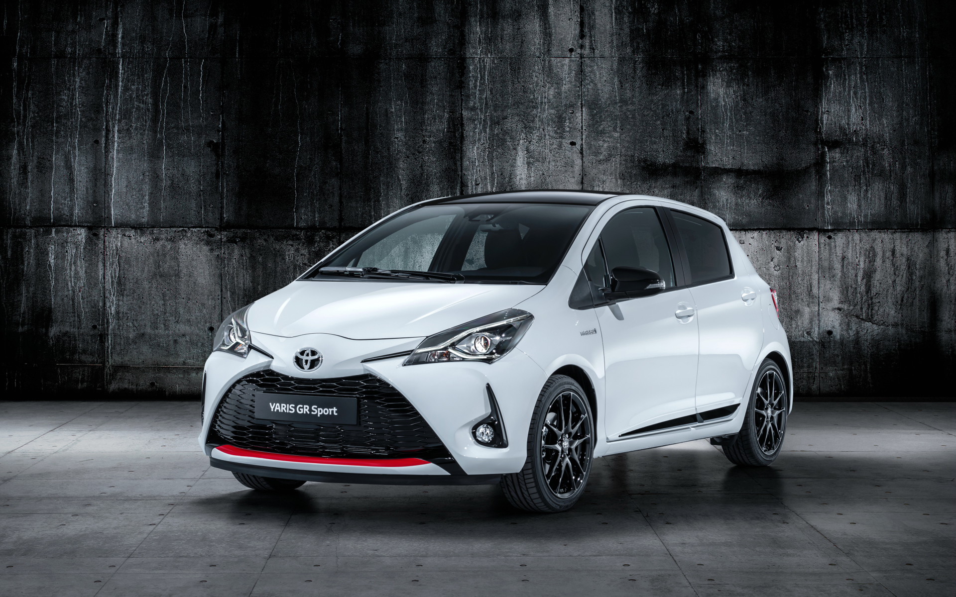Белый автомобиль Toyota Yaris на сером фоне 