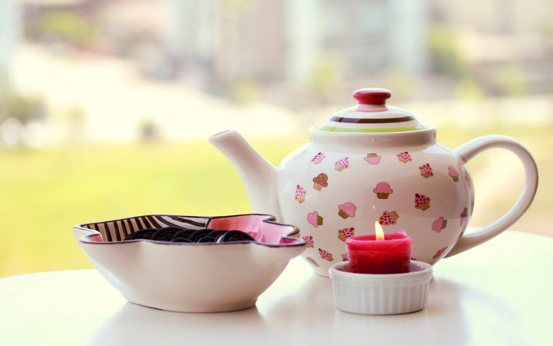 Чайник с печеньем орео и зажженной свечей на столе