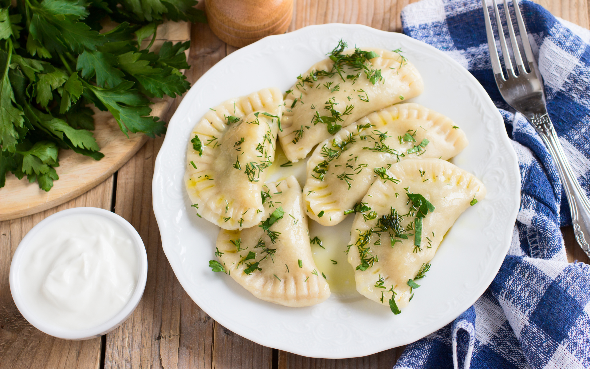 Вареники с зеленью на белой тарелке 