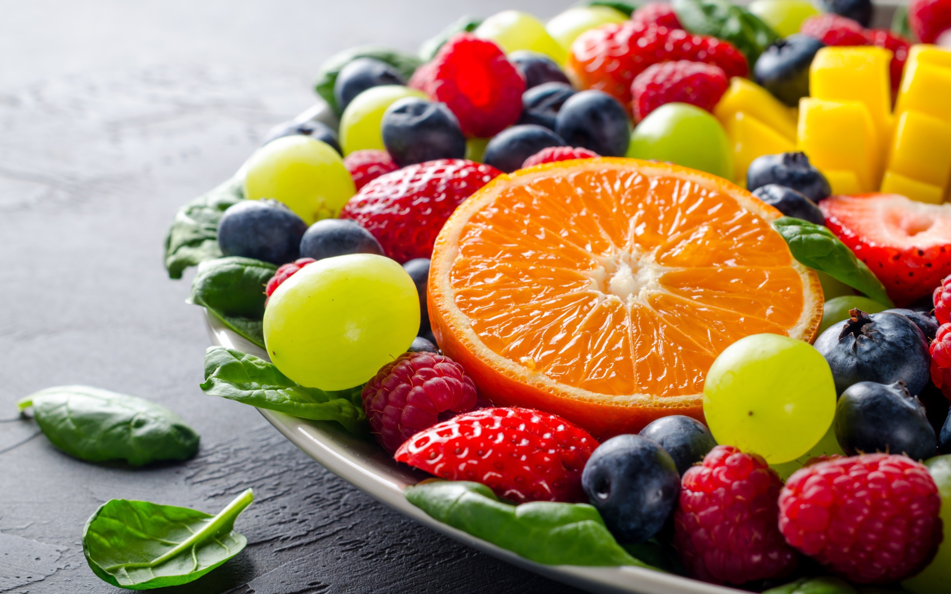 Аппетитные ягоды на тарелке с зелеными листьями базилика