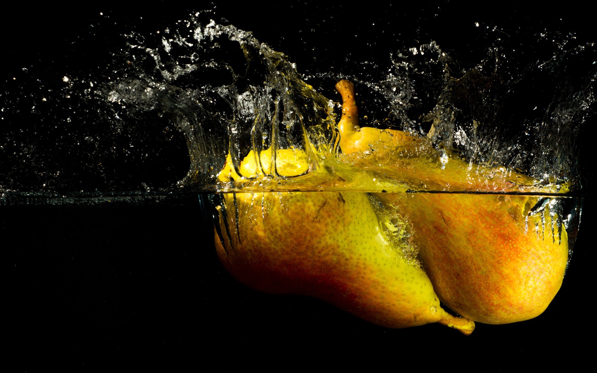 Груши в воде с брызгами на черном фоне