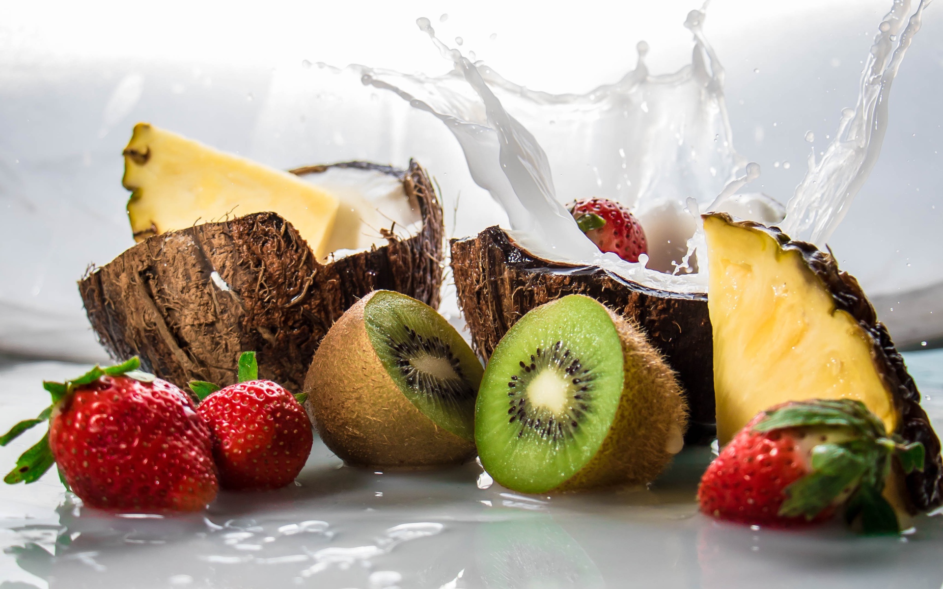 Тропические фрукты кокосы, ананасы и киви на белом фоне с клубникой