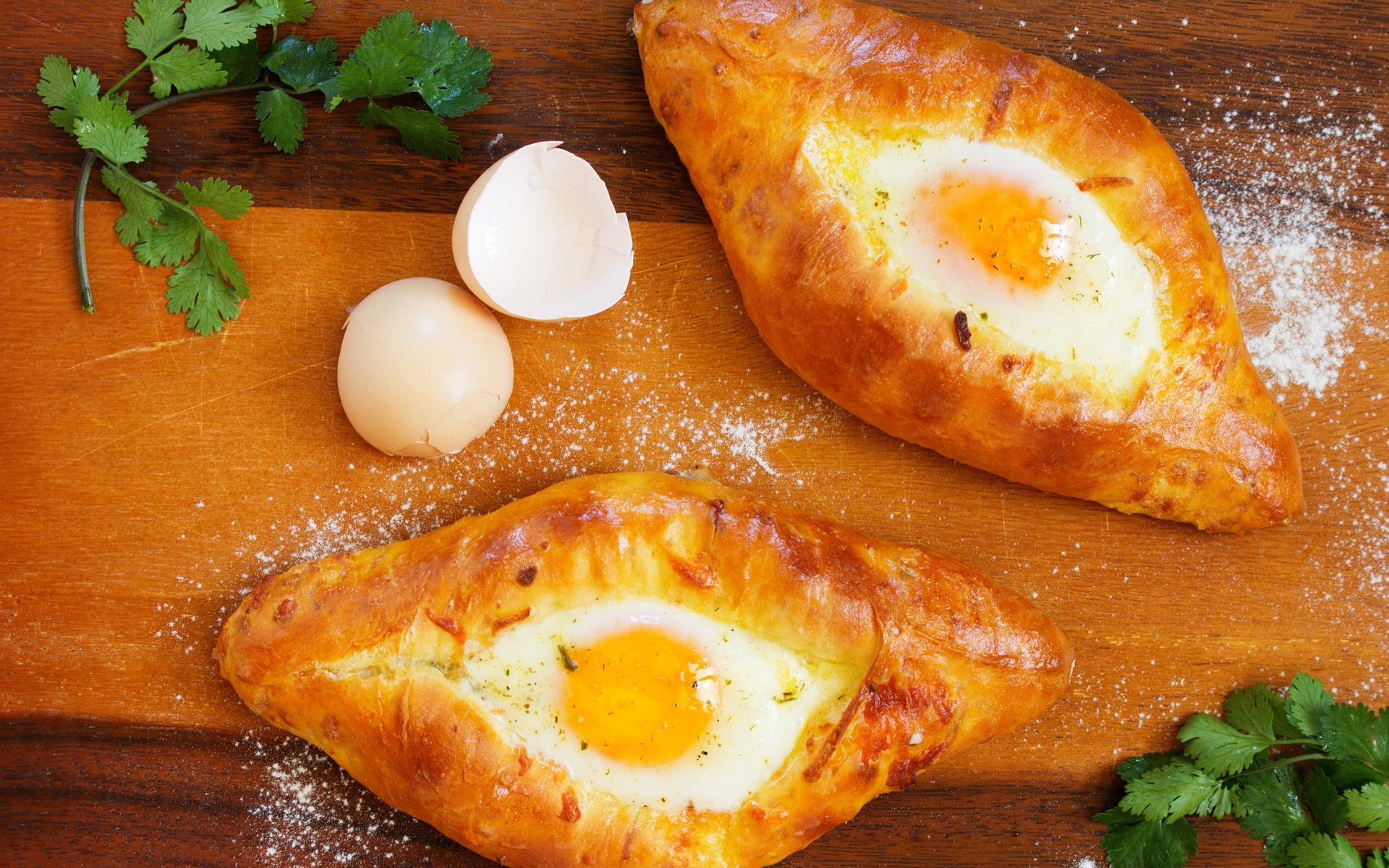 Две булки с яйцом, скорлупой и зеленью на столе