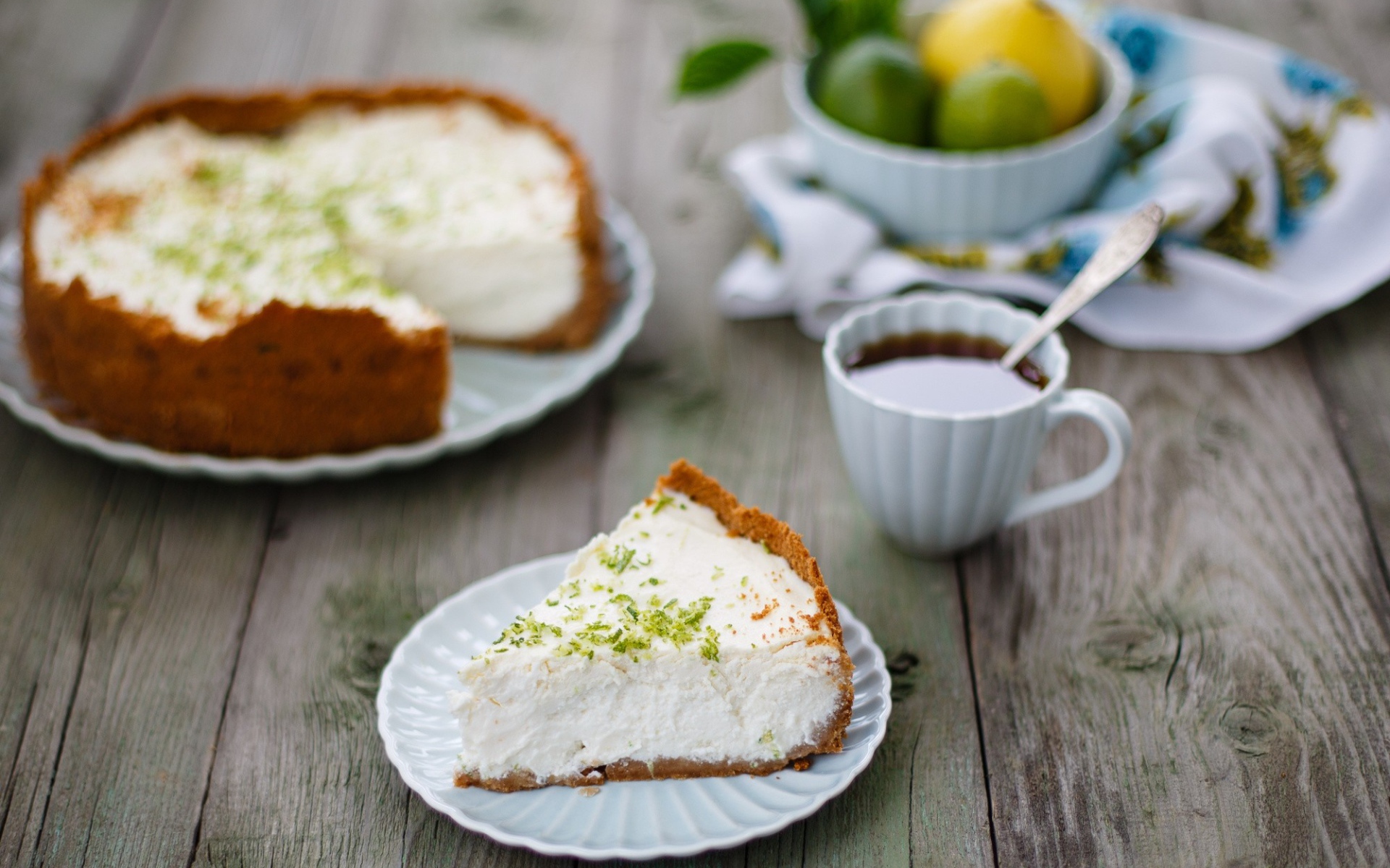 Кусок чизкейка на столе с чашкой чая