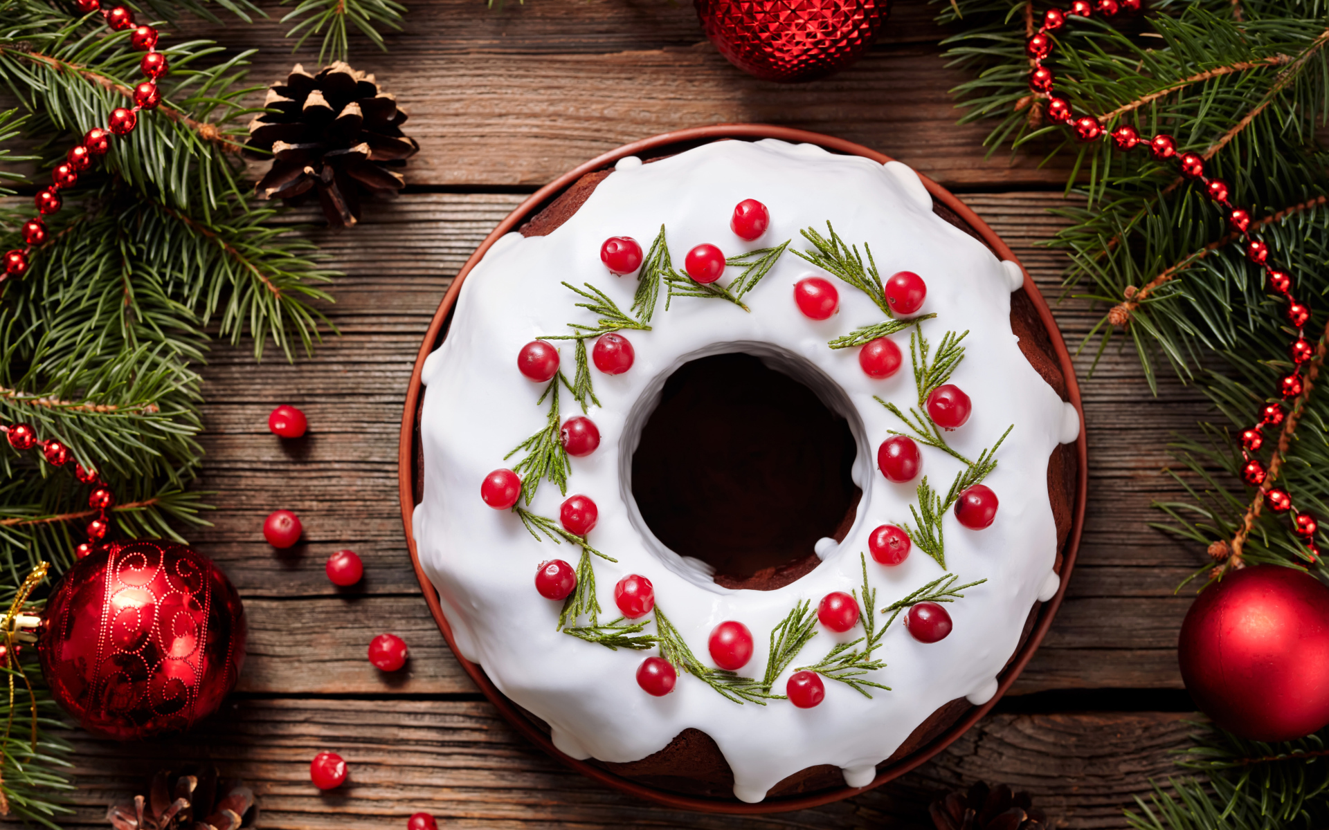 Рождественский пирог с ягодами клюквы на деревянном столе с еловыми ветками