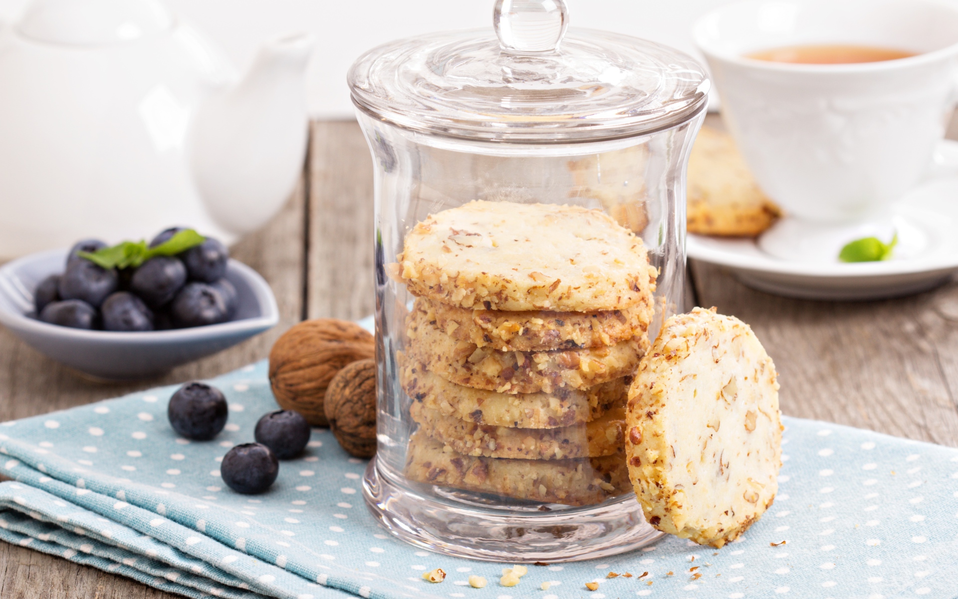 Печенье в стеклянной банке на столе с орехами и черникой
