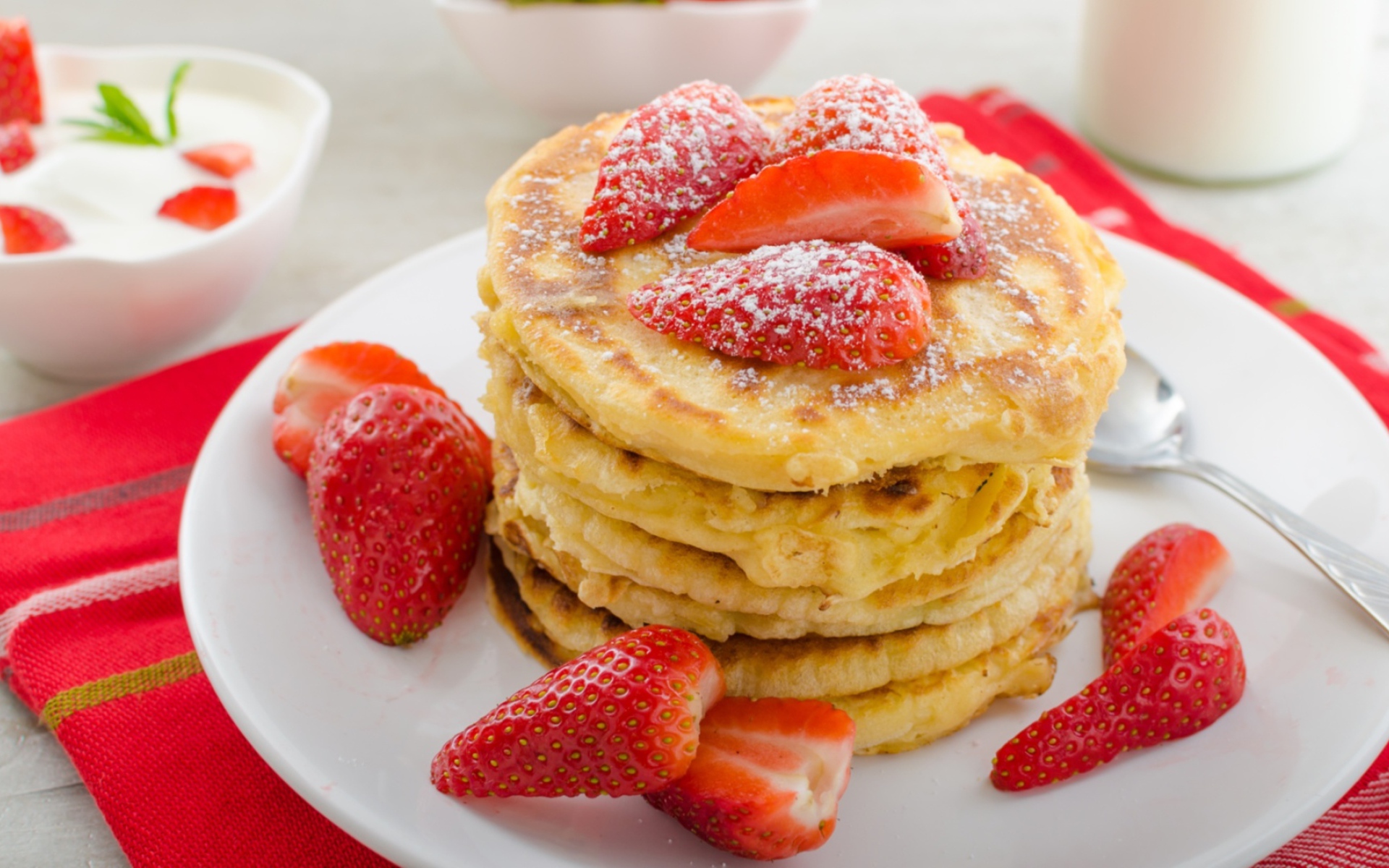 Оладьи с клубникой и сахарной пудрой на белой тарелке 