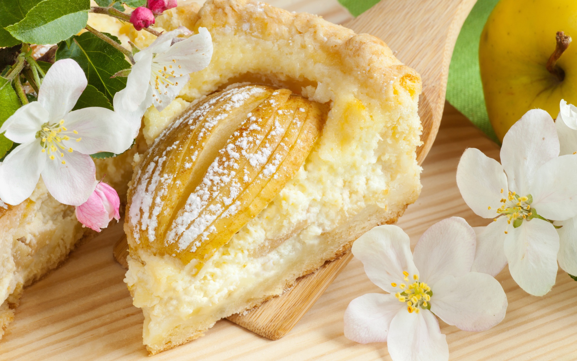 Кусок пирога с яблоками на деревянной лопатке с цветами яблони