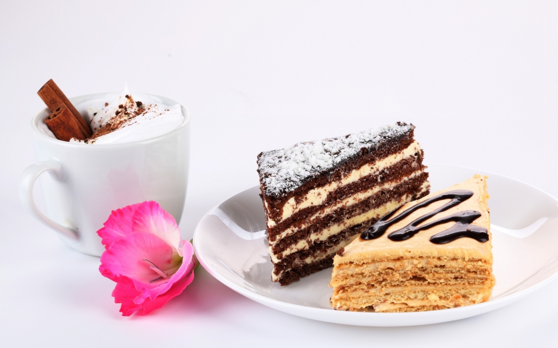 Два куска торта на столе с чашкой кофе и розовым цветком