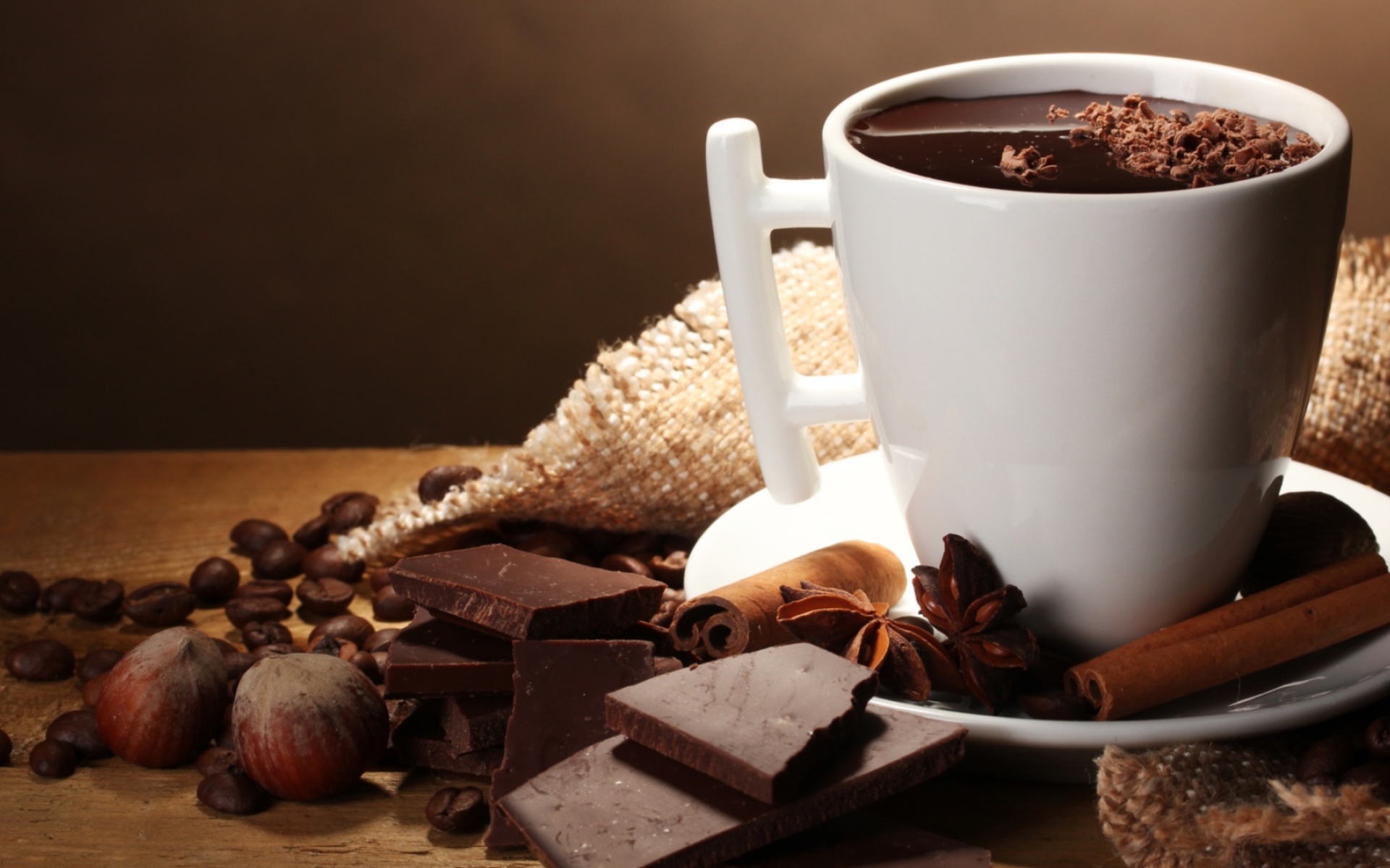 Чашка горячего шоколада на столе с корицей, бадьяном и фундуком