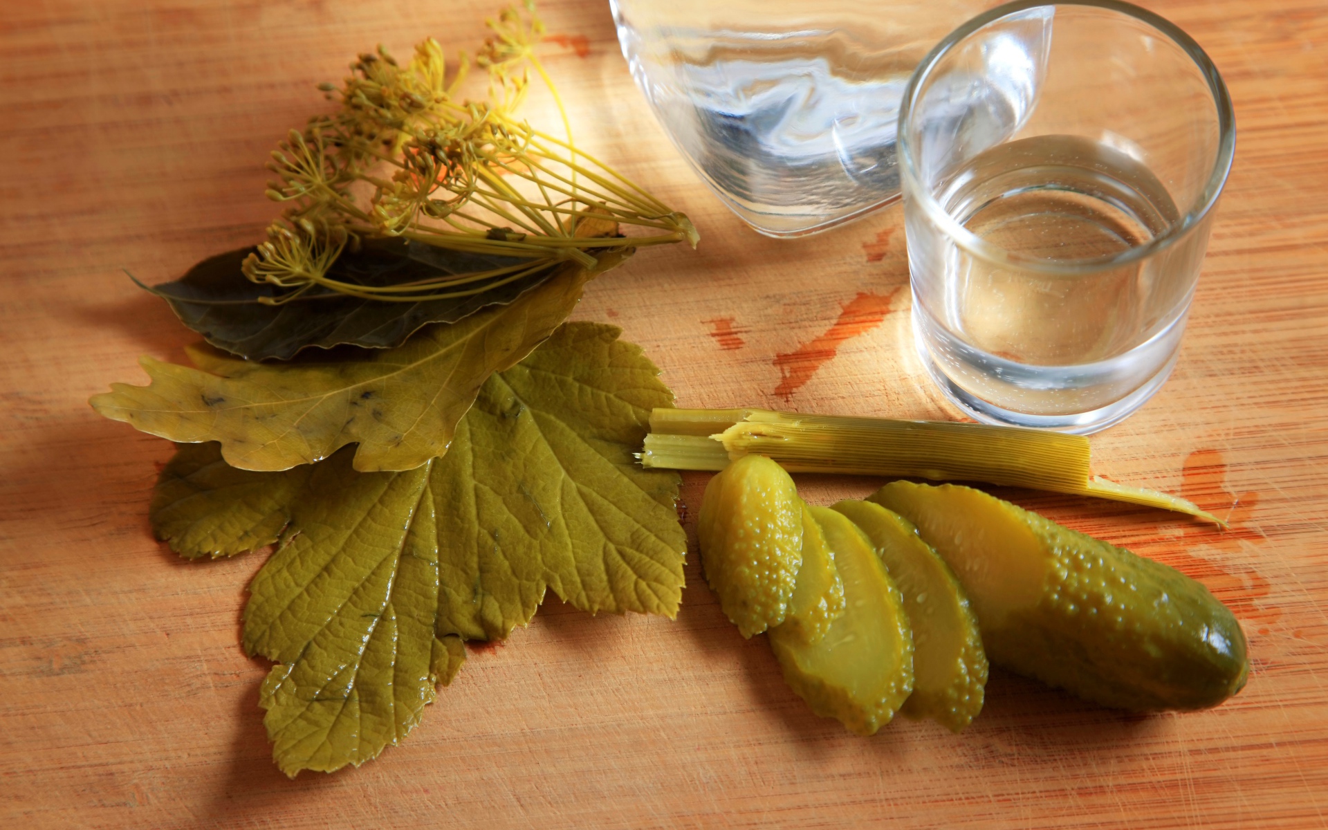 Рюмка водки на столе с соленым огурцом