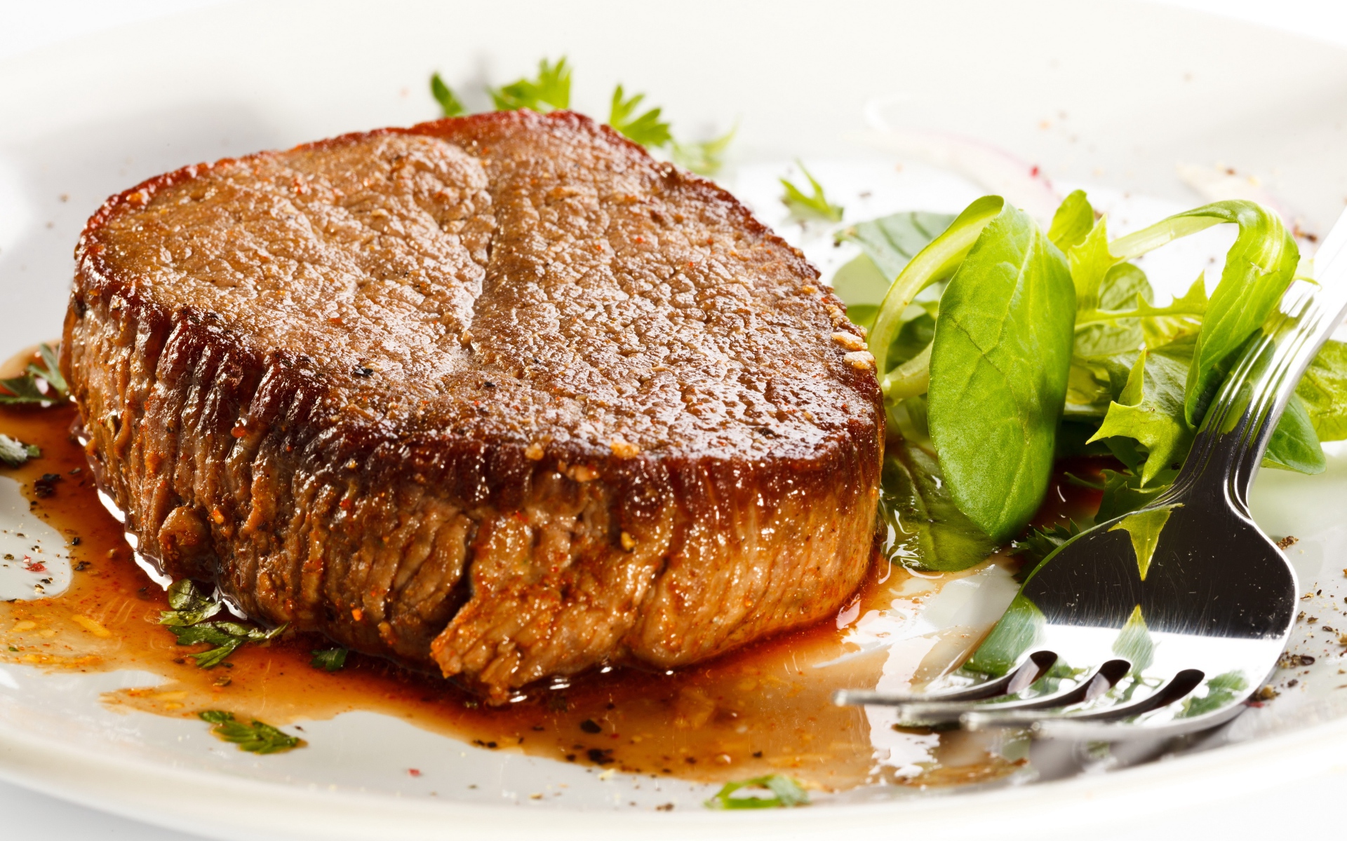 Отбивная с зеленым салатом на тарелке с вилкой