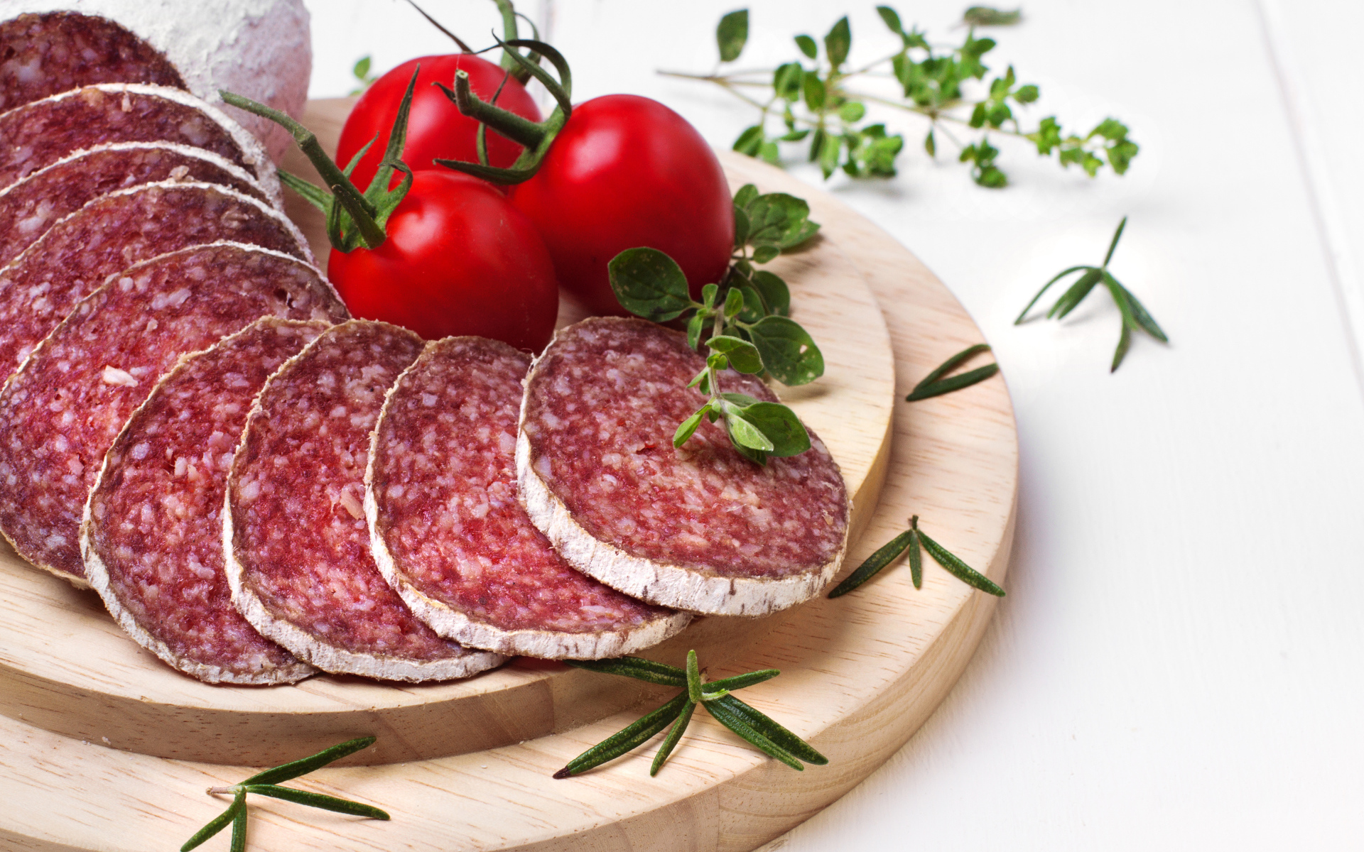 Вкусная колбаса на разделочной доске с помидорами и зеленью 