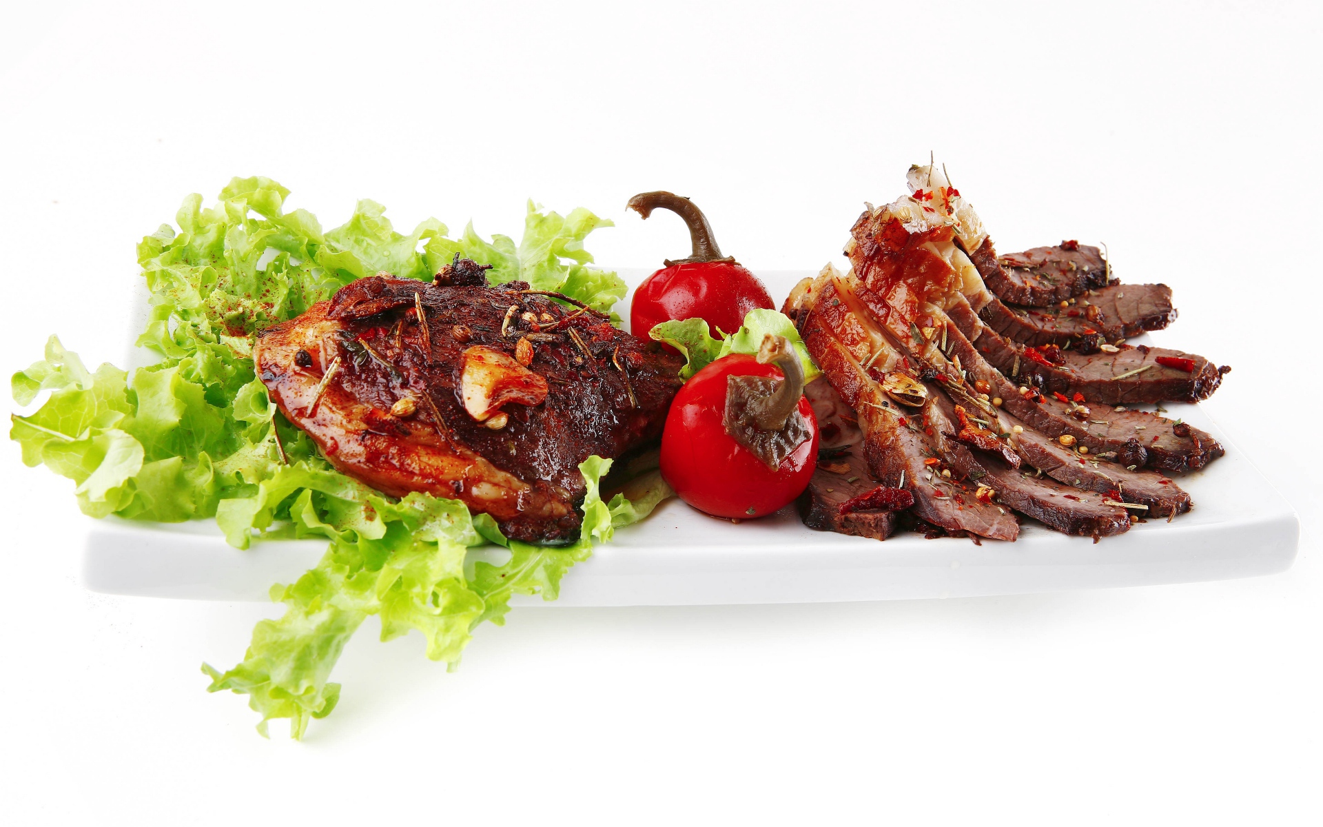 Мясо с листьями салата и красным перцем на белом фоне