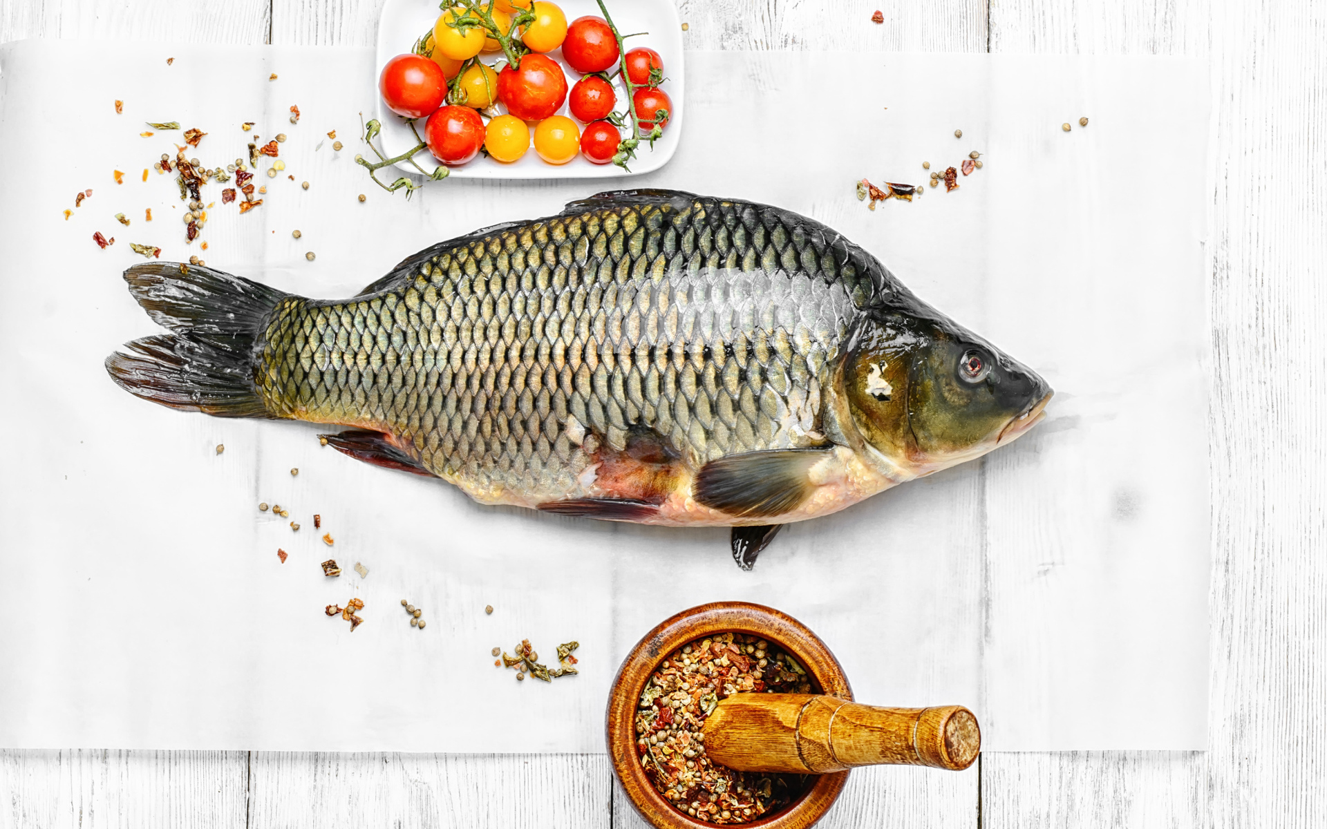 Свежий карась на столе со специями и помидорами