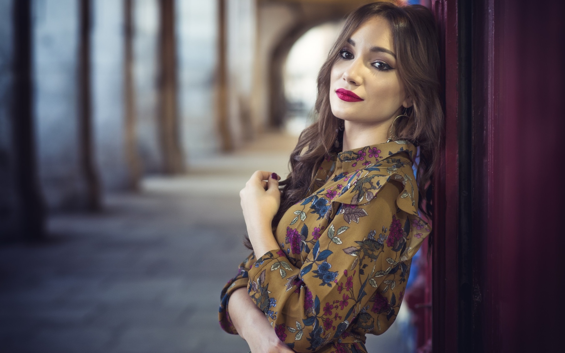 Девушка шатенка в красивом платье у стены