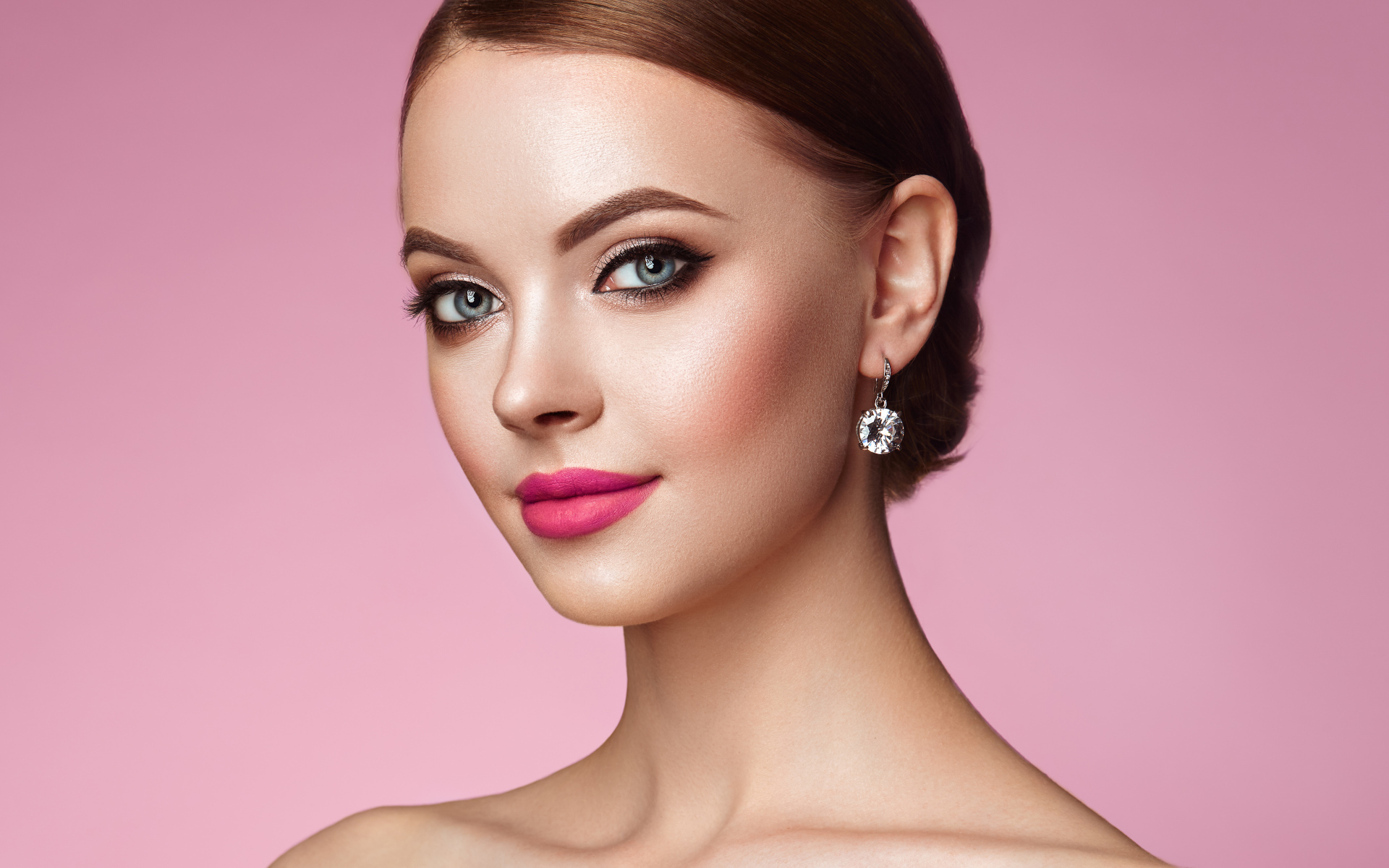Красивая голубоглазая девушка с красивыми серьгами на розовом фоне
