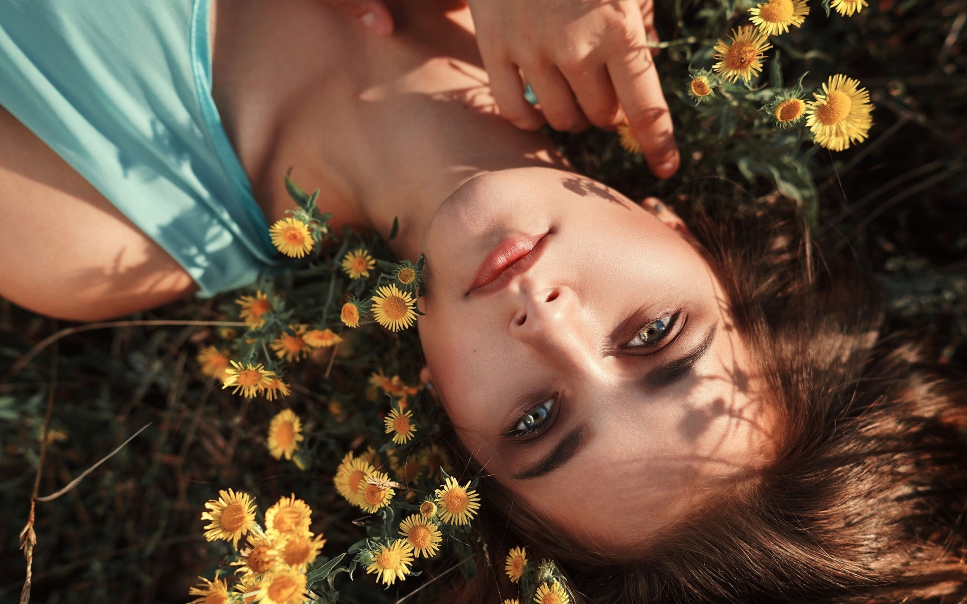 Красивая шатенка лежит на земле с желтыми цветами