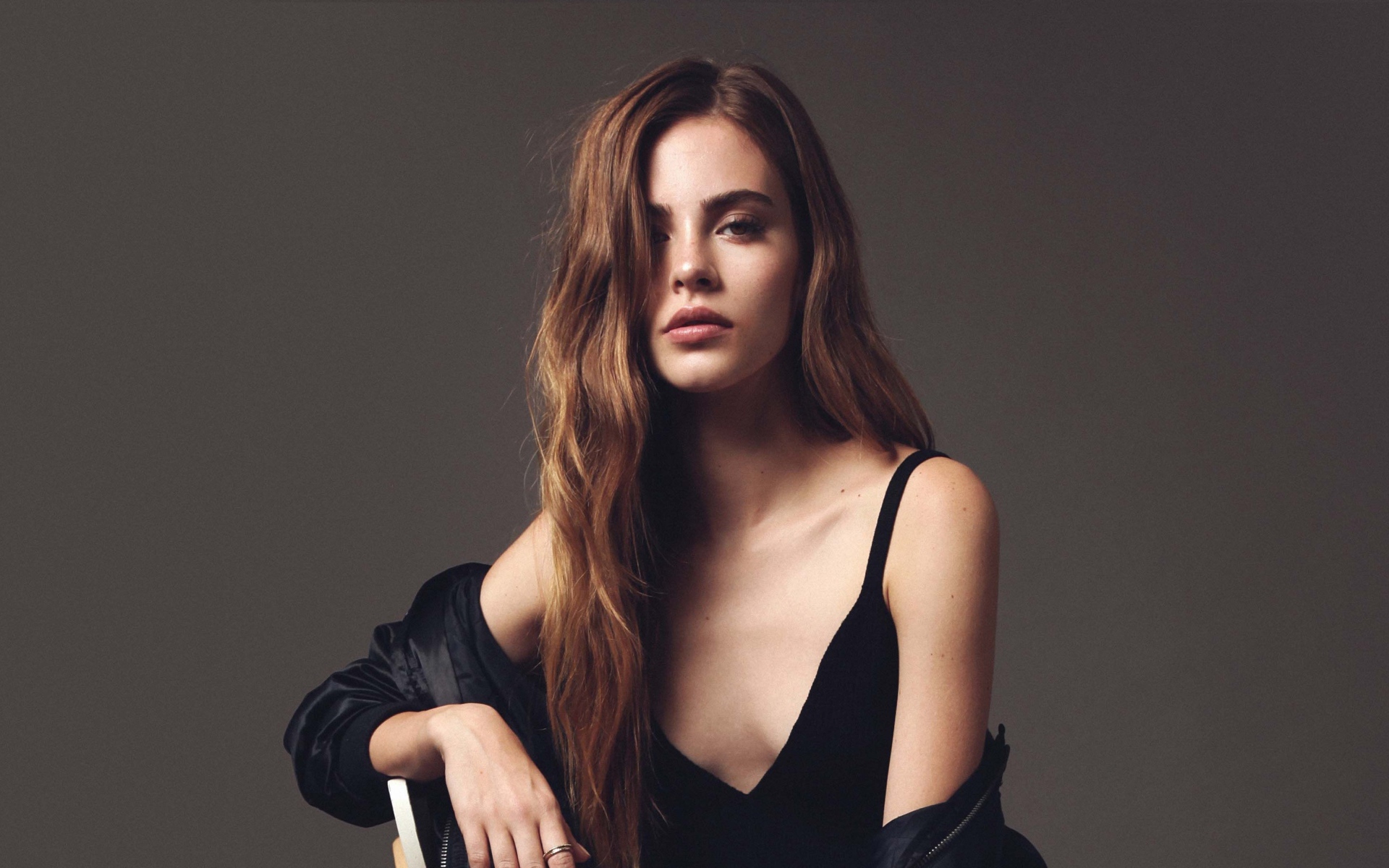 Красивая брюнетка в черном платье сидит на стуле