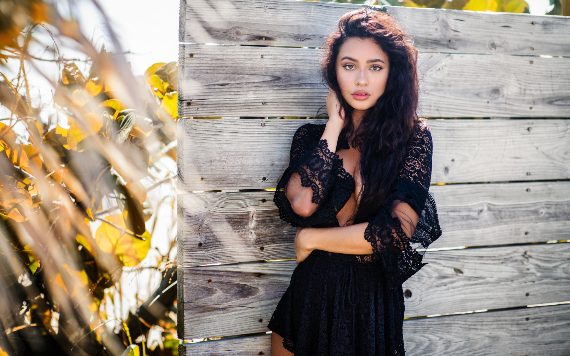 Красивая девушка в черном платье у стены 