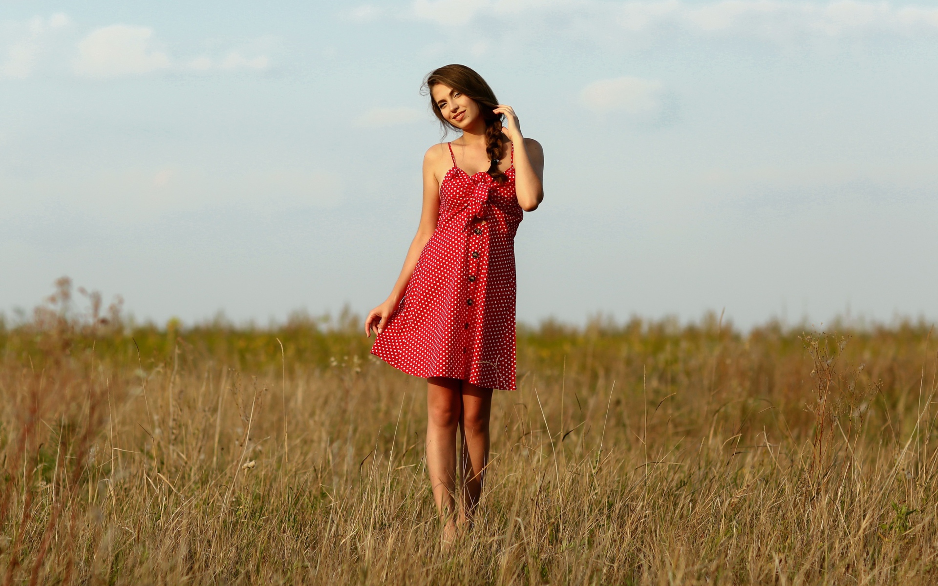 Красивая девушка в красном сарафане на поле 