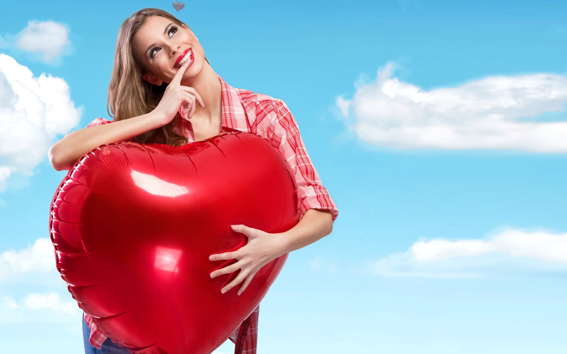 Красивая девушка с большим воздушным шаром в форме сердца на фоне неба