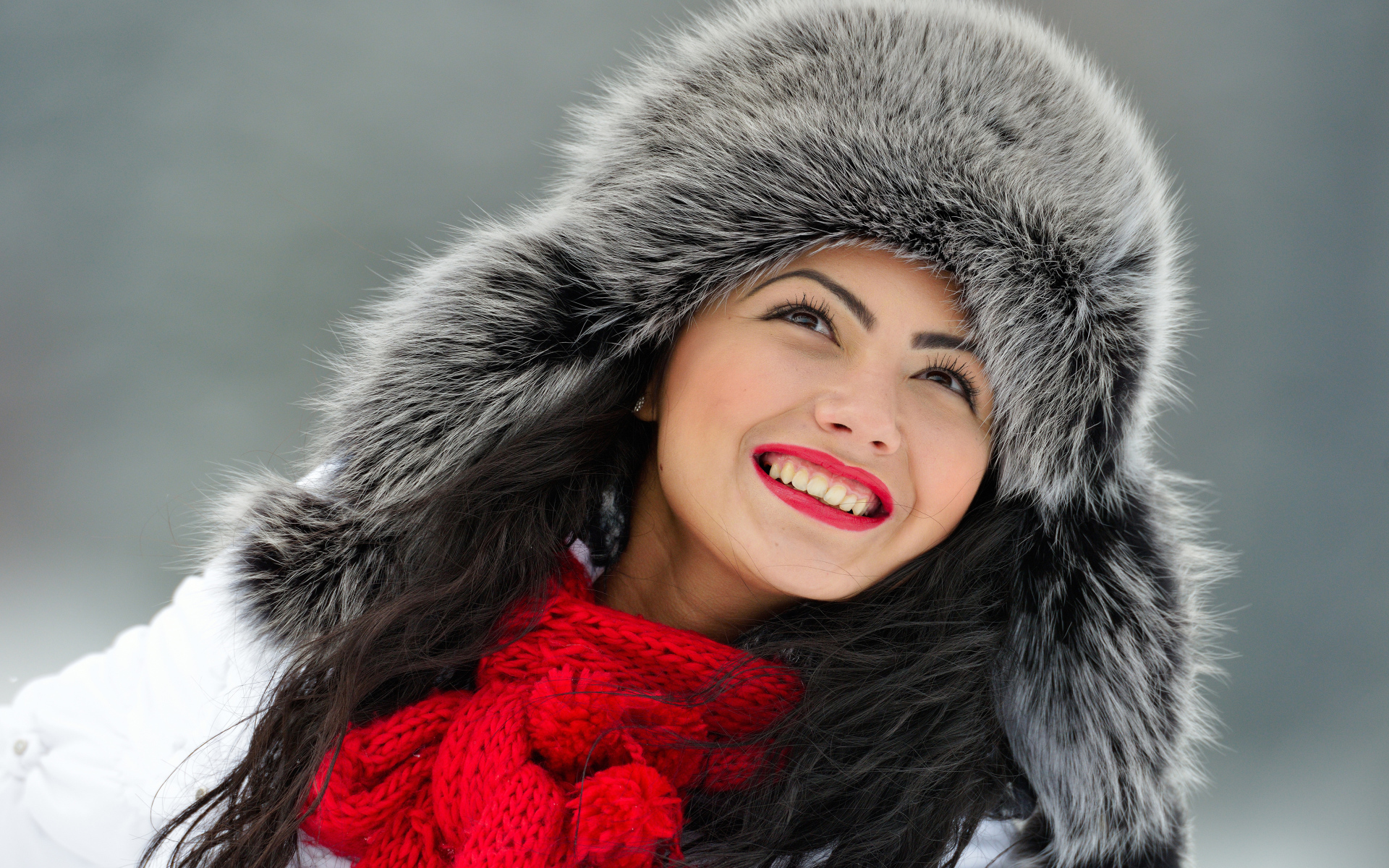 Красивая улыбающаяся брюнетка в теплой зимней шапке