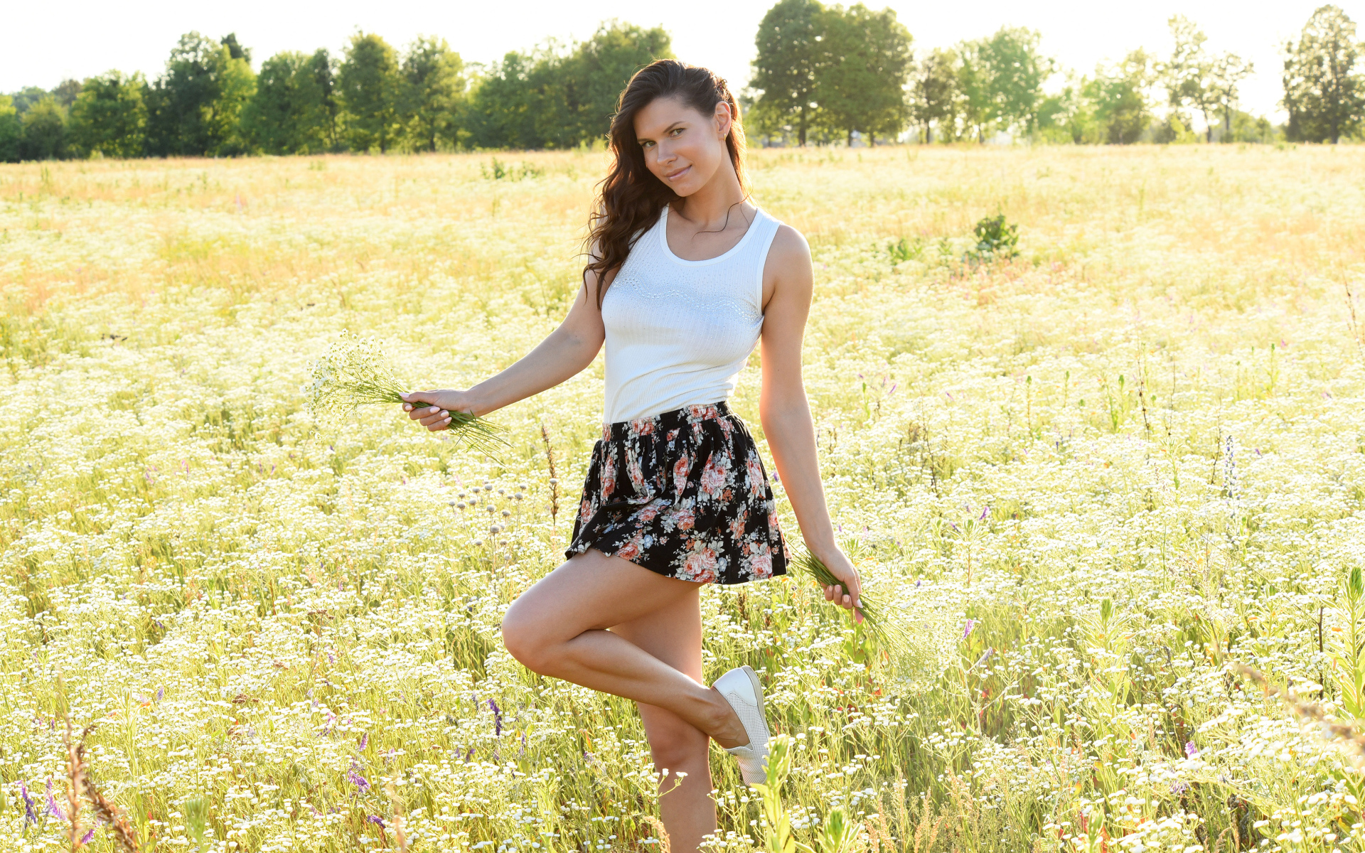 Красивая молодая девушка на поле с белыми ромашками