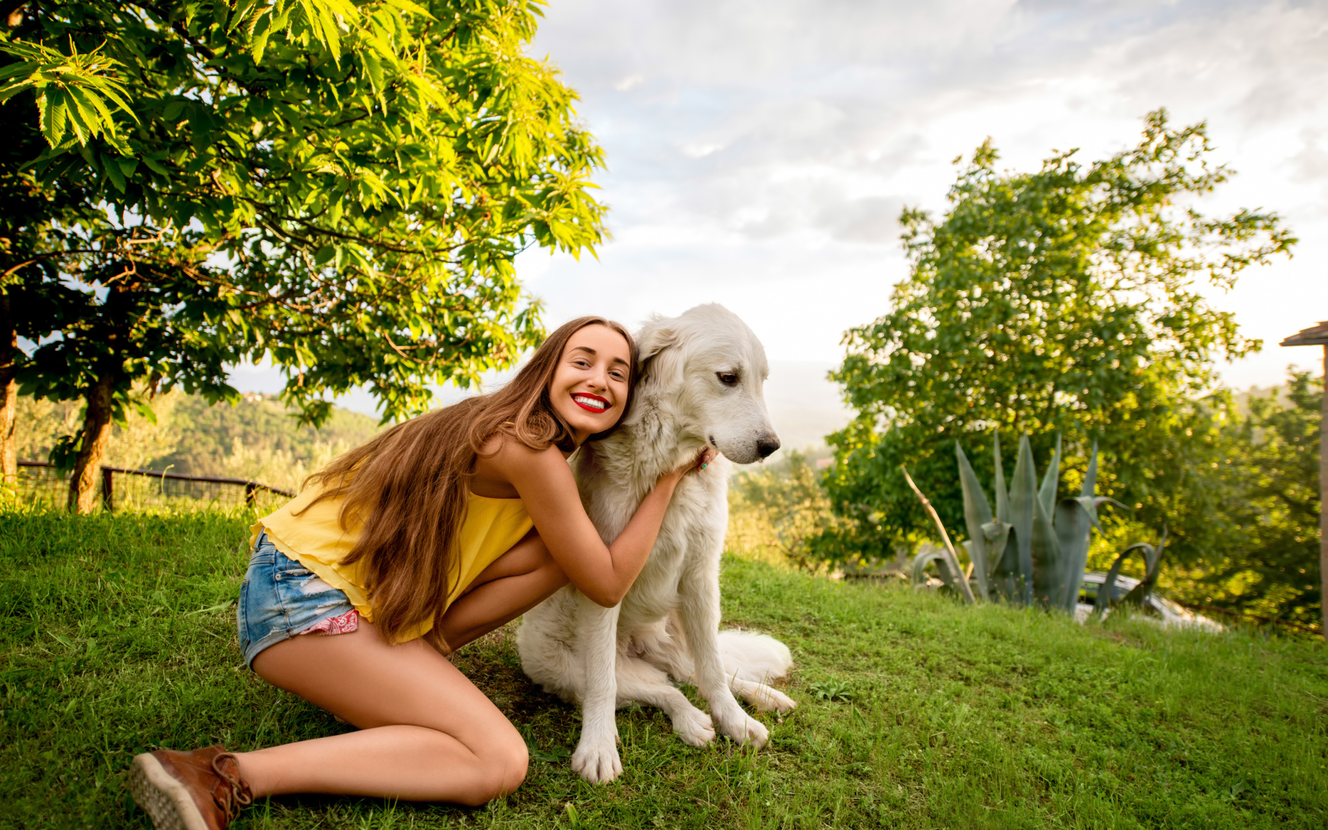Улыбающаяся шатенка с золотистым ретривером на зеленой траве летом