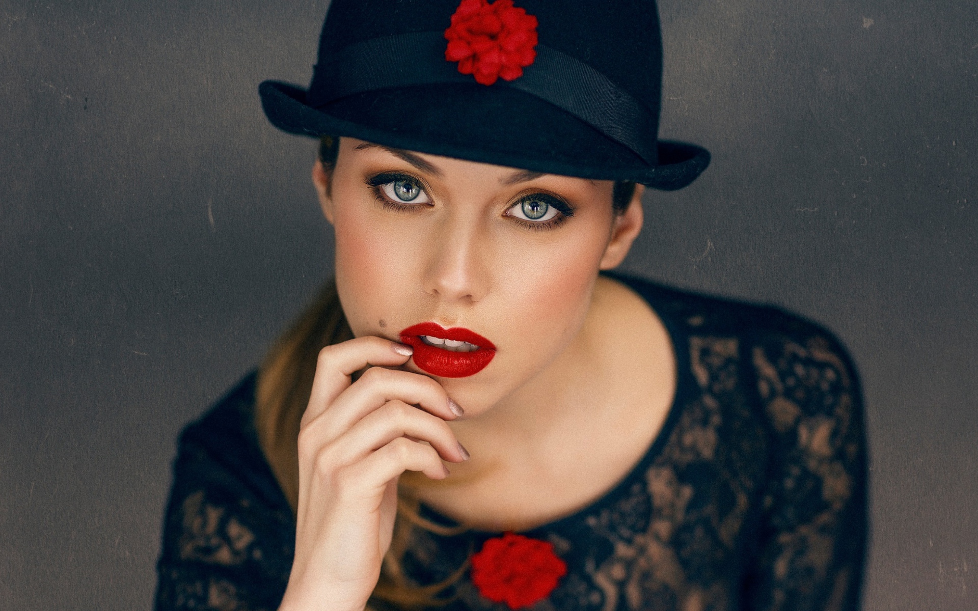 Стильная девушка с ярким макияжем в черной шляпе 
