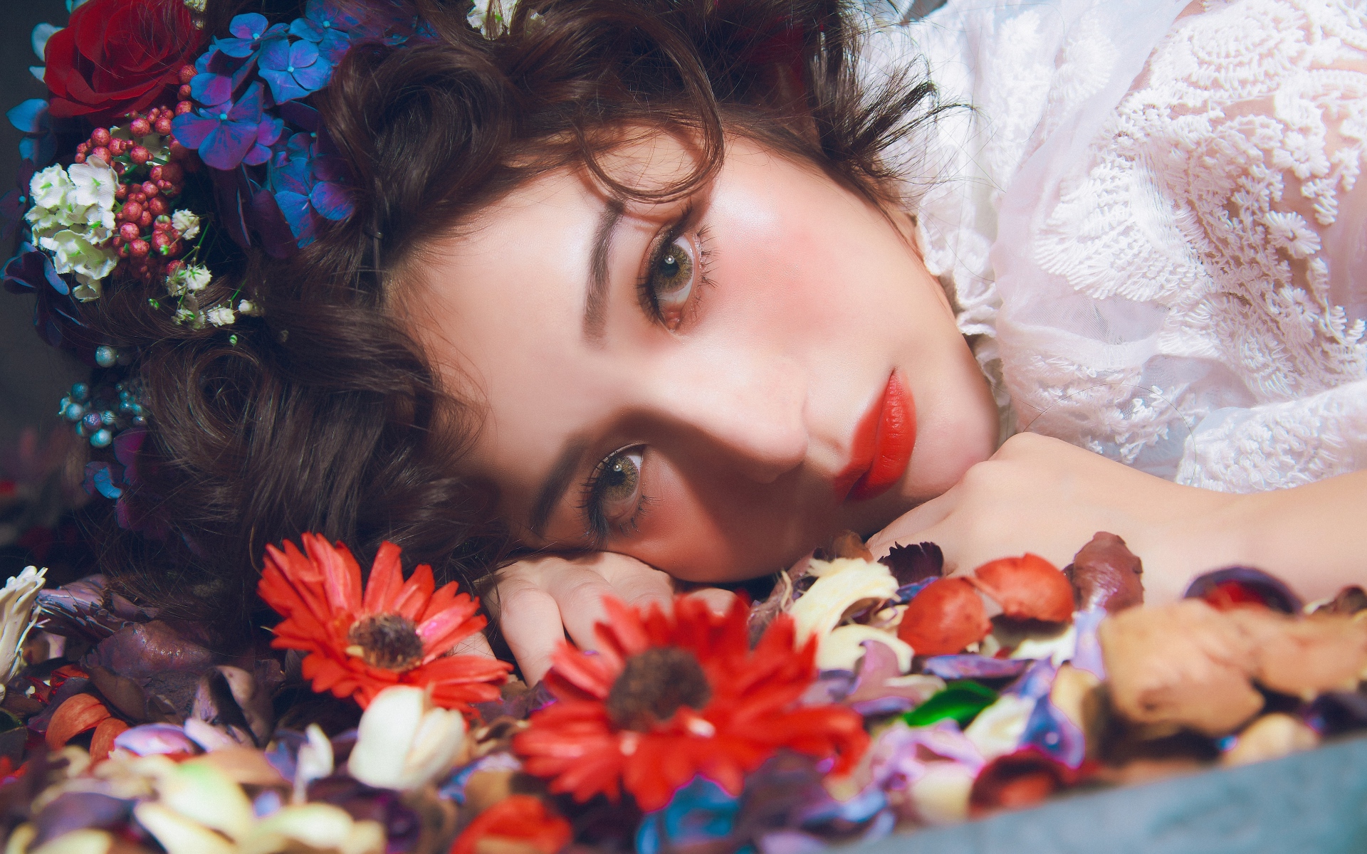 Молодая красивая девушка лежит цветами в волосах