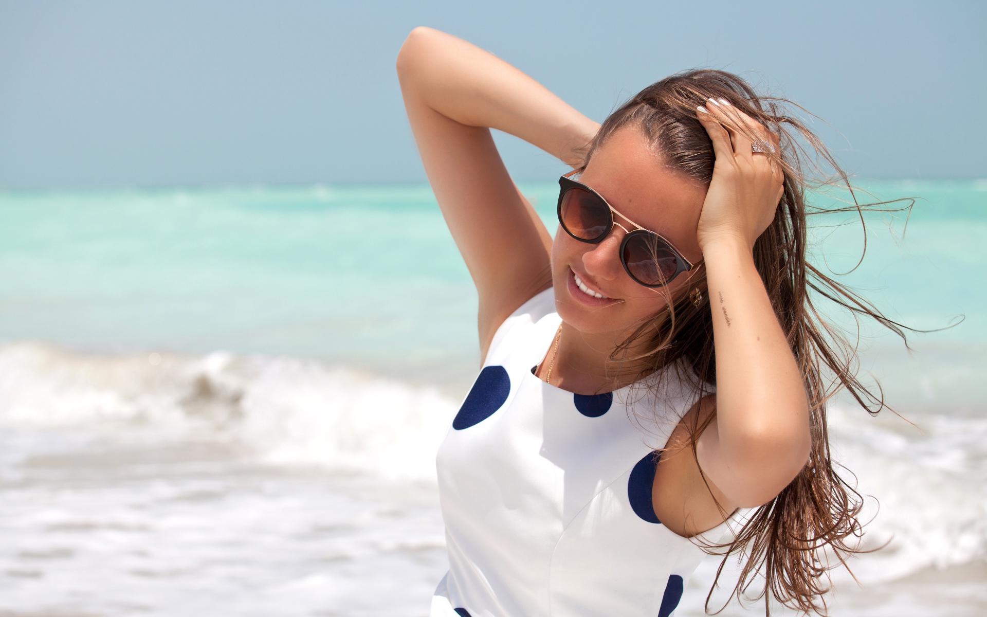Молодая шатенка в солнечных очках у моря