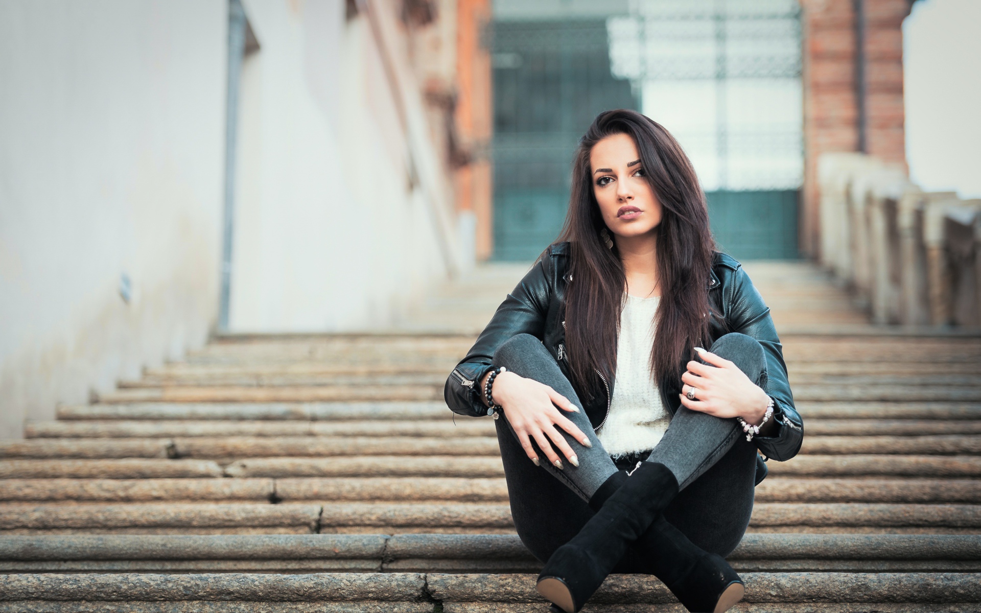Молодая брюнетка сидит на ступеньках