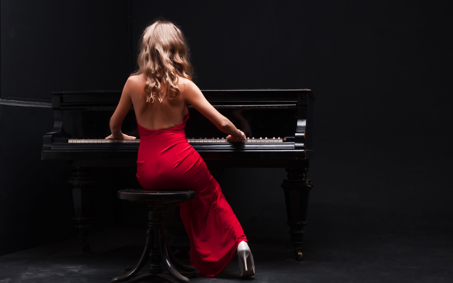 Молодая девушка в красном платье играет на пианино